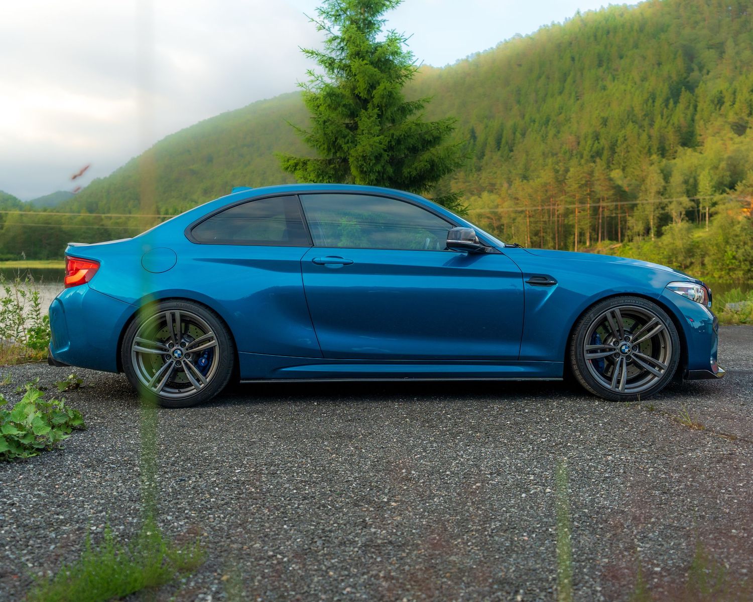 A bright blue BMW M4 photographed from different angles in a mountain setting.
