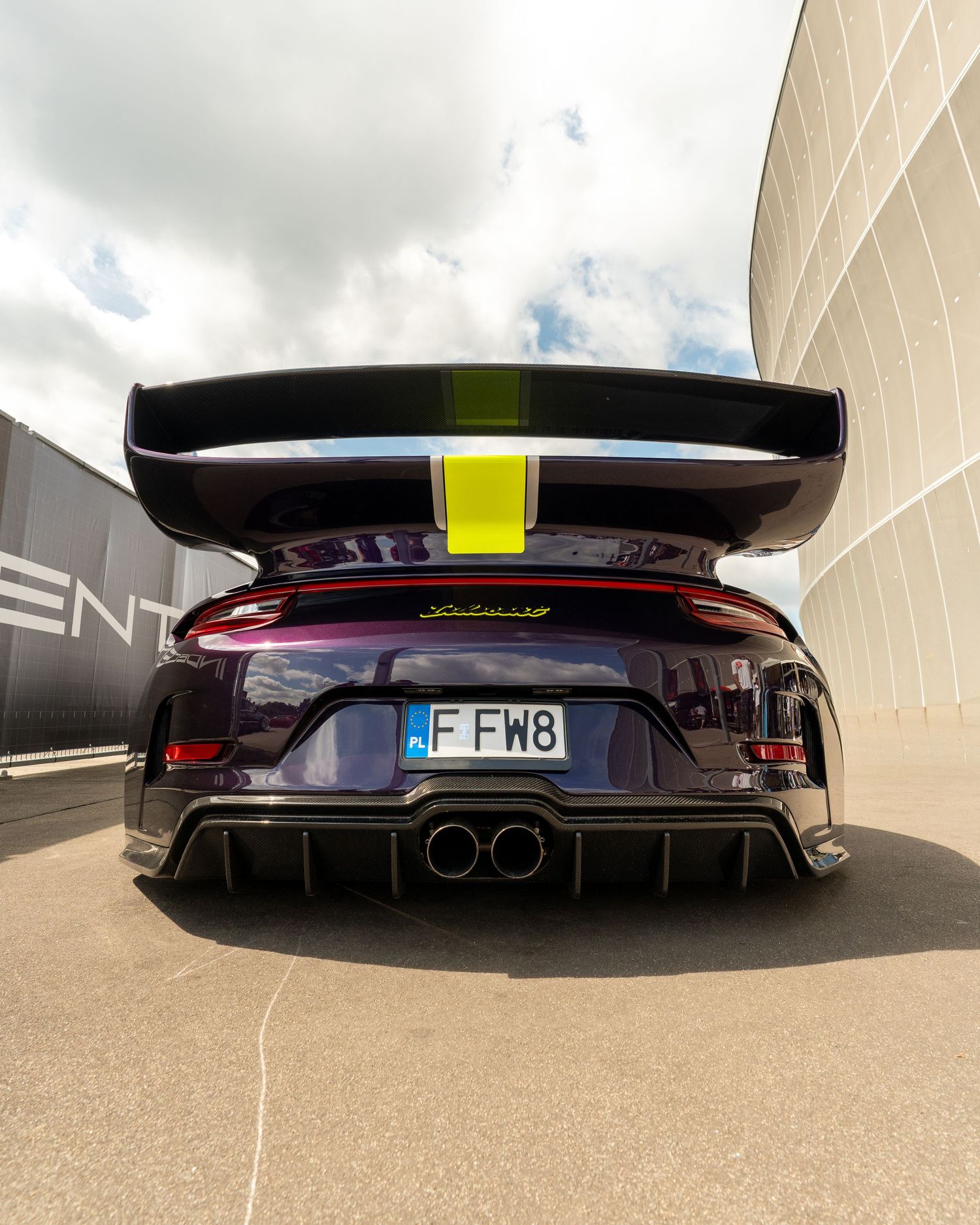 Rear view of a black sports car with large rear wing and dual exhaust setup.