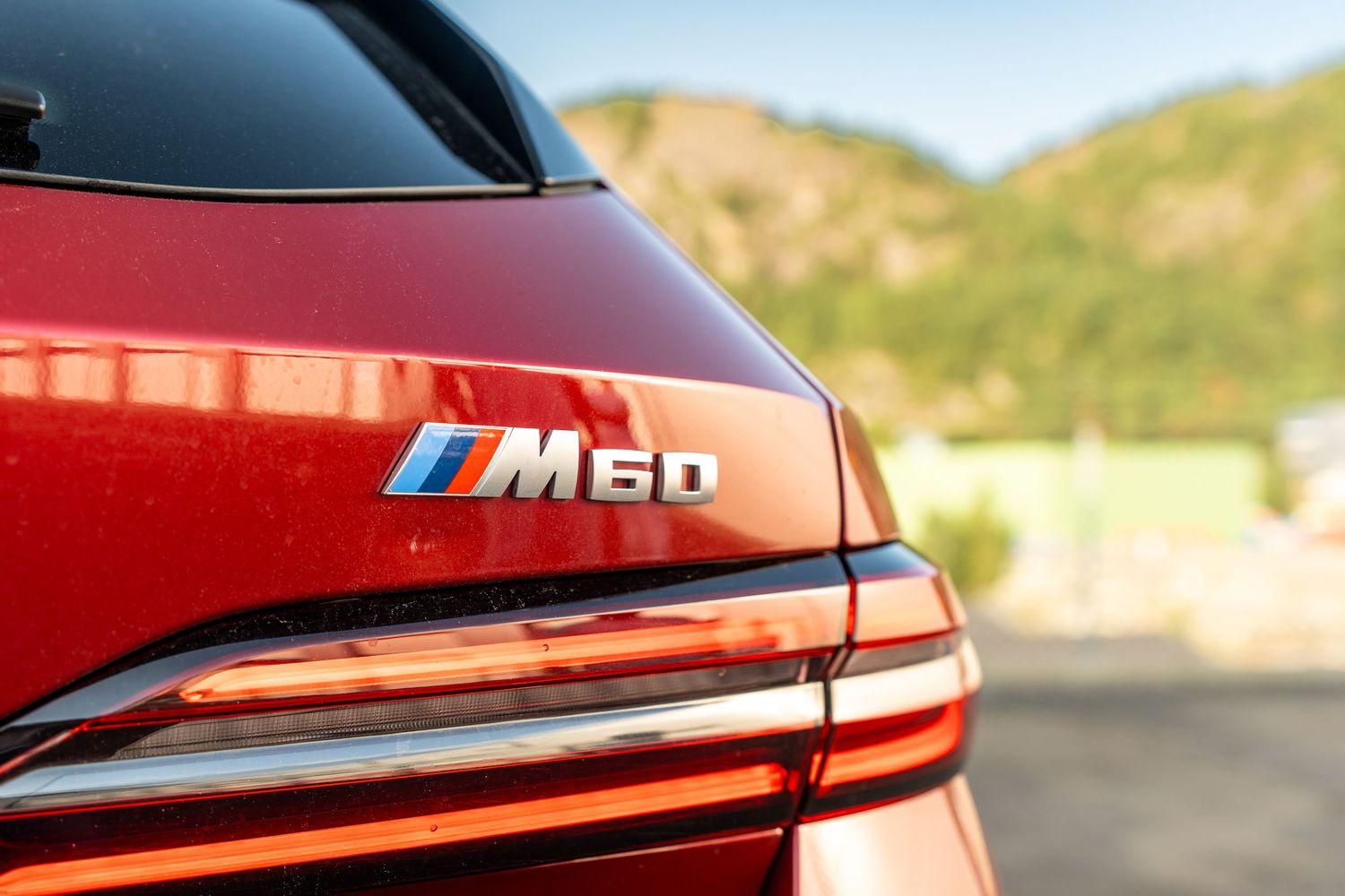 Close-up shots of a red BMW M30 exterior trim and badging against a mountain backdrop.