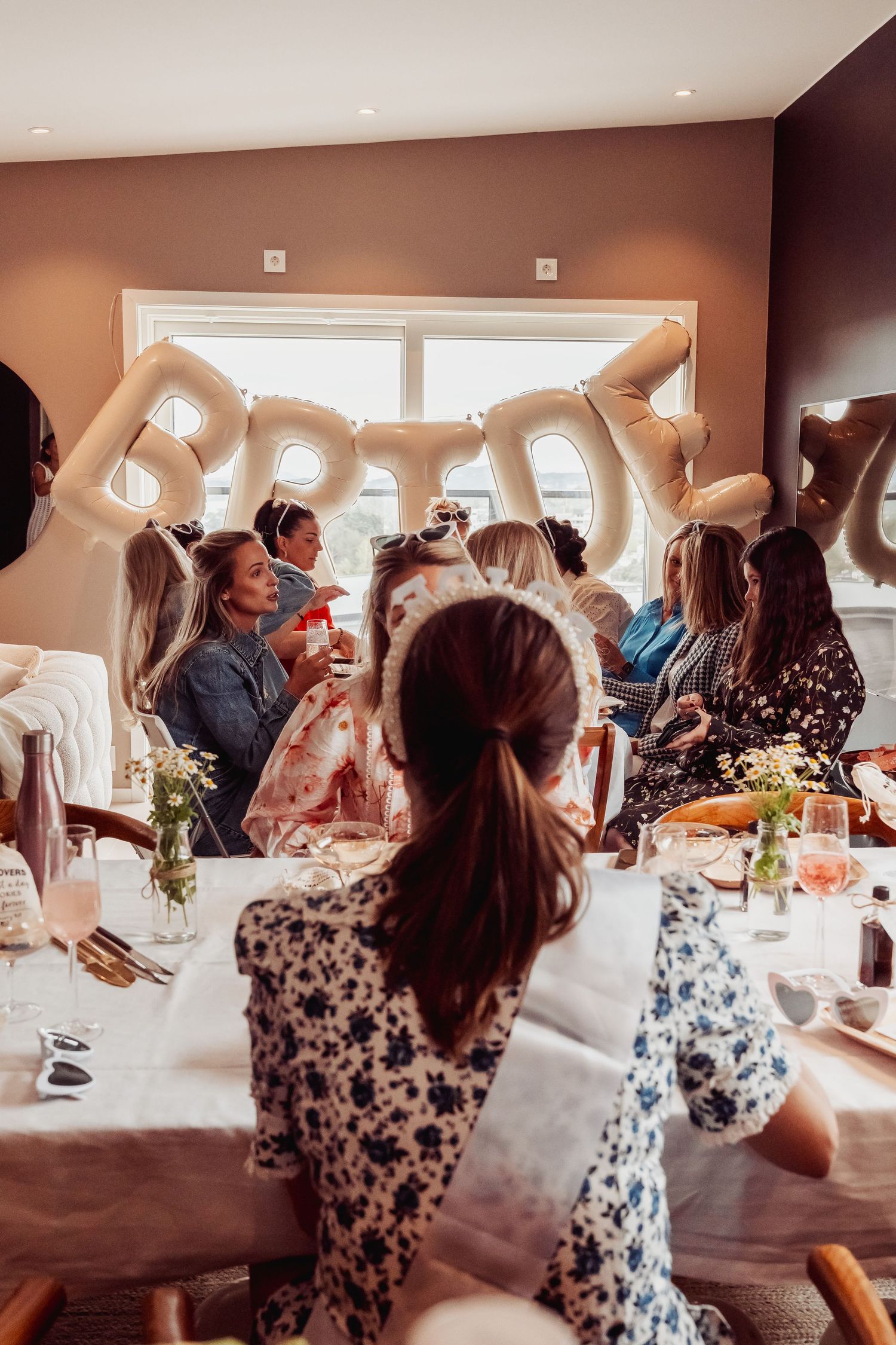 Birthday celebration with balloon letters and guests gathered around dining table.