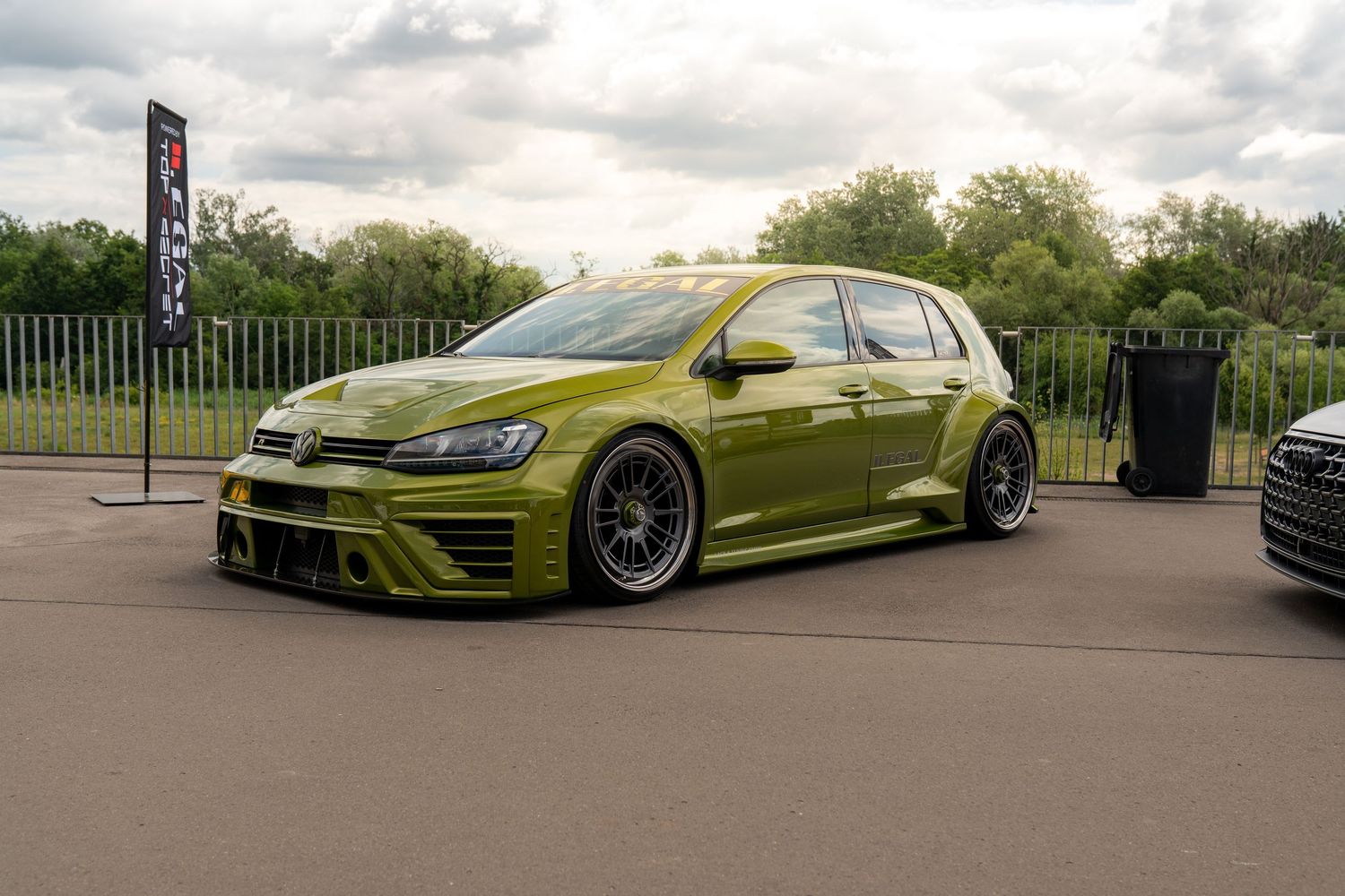 Slammed metallic green Volkswagen Golf R with aftermarket wheels and body kit.