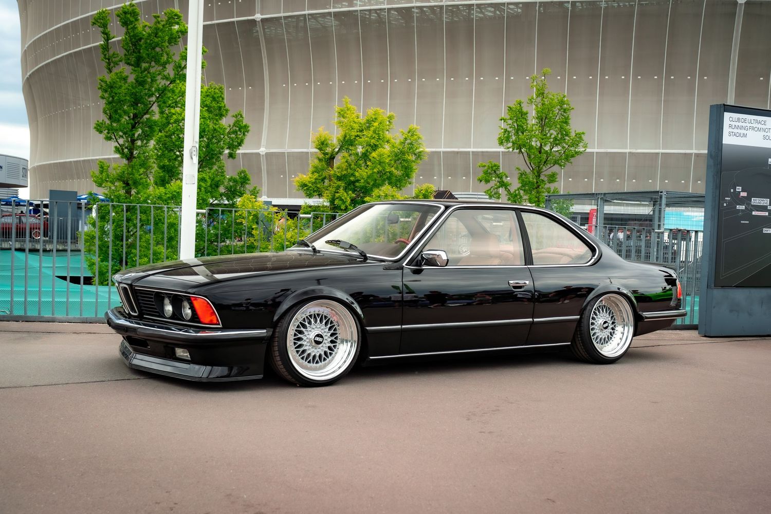 Black vintage BMW 6-series with period-correct BBS wheels parked at a show.