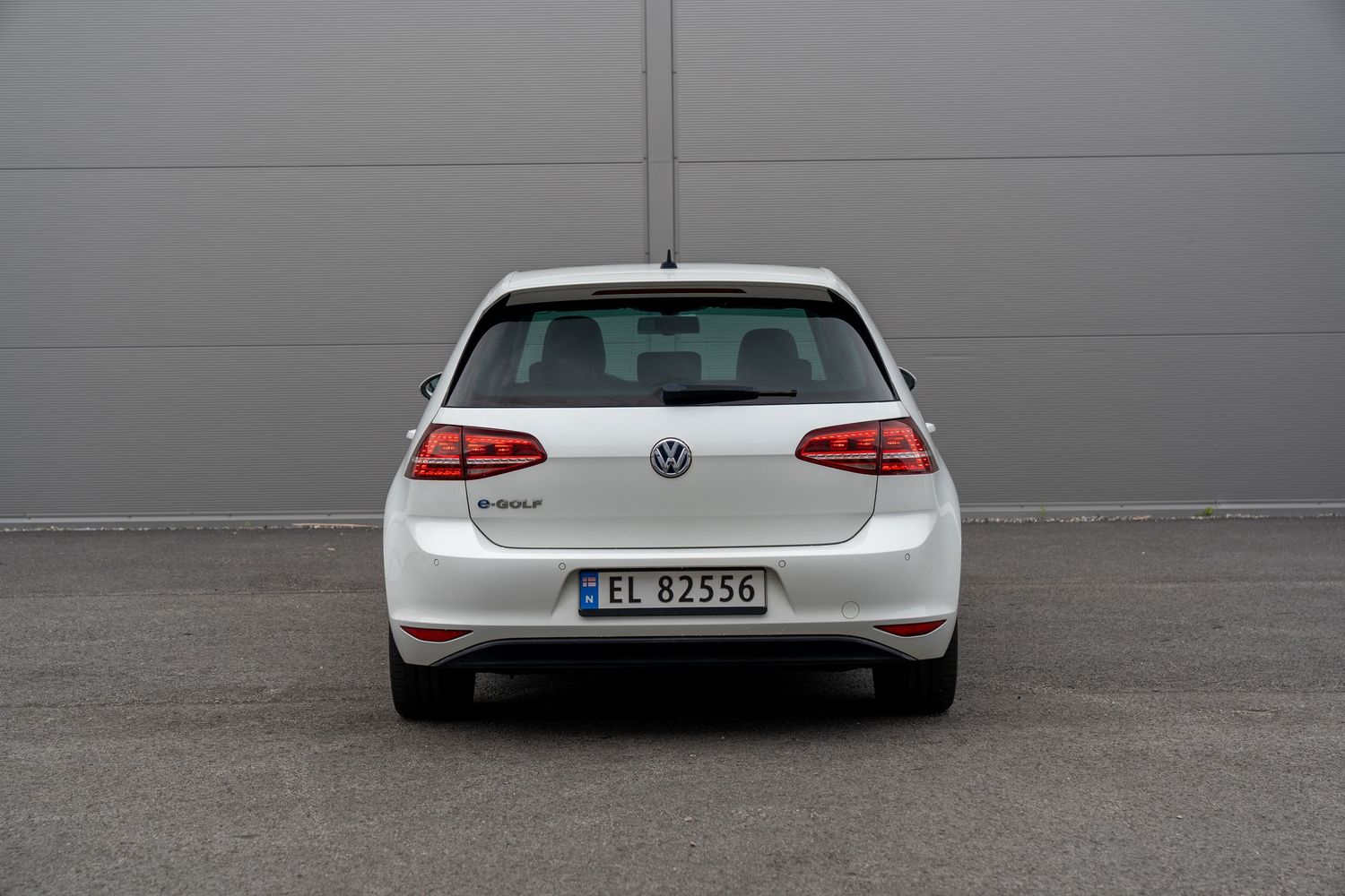 Rear view of a silver Volkswagen Golf hatchback parked in front of gray wall showing taillights and badging.