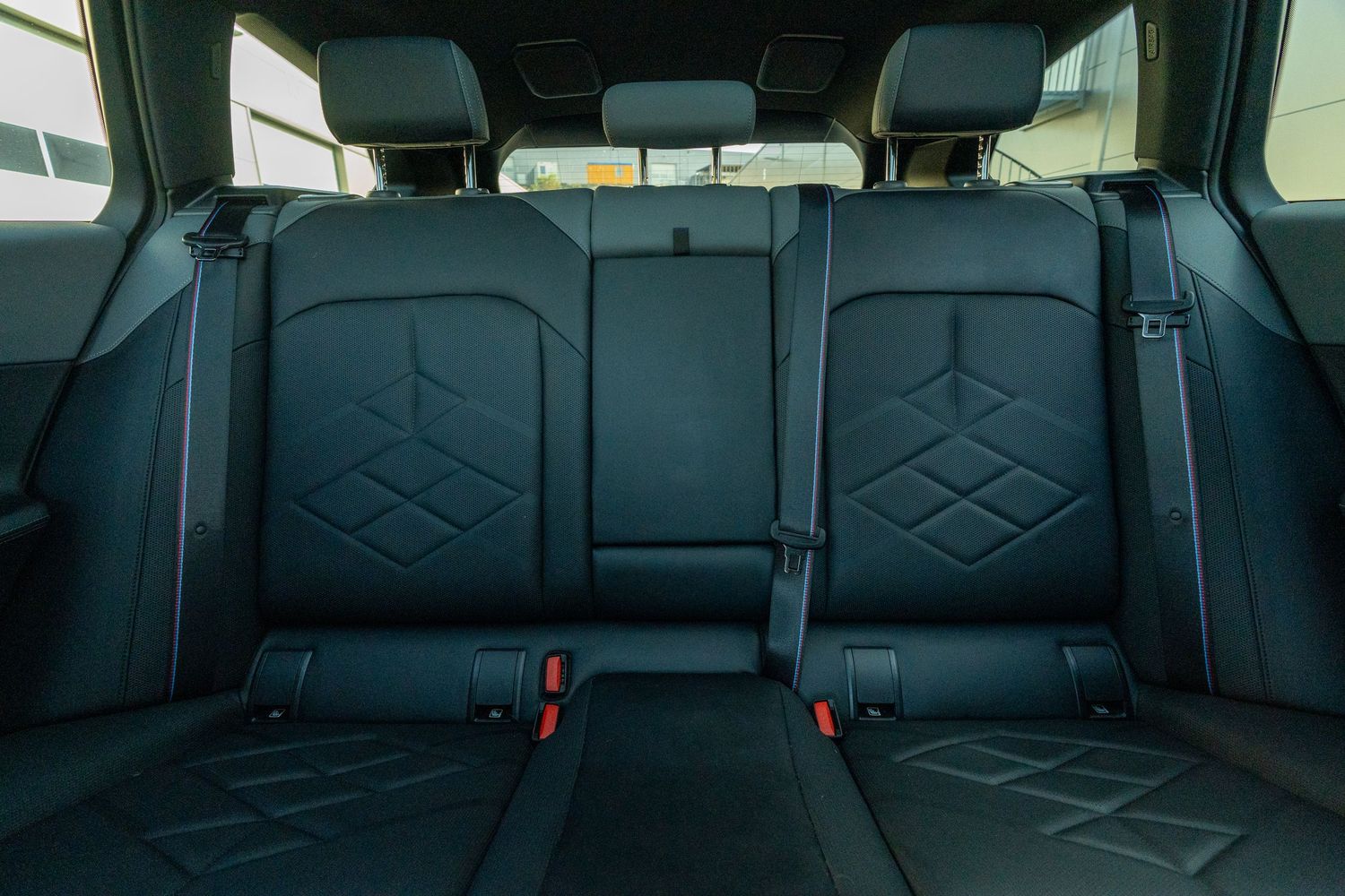 Rear seats of BMW with diamond-pattern stitching and black leather upholstery.