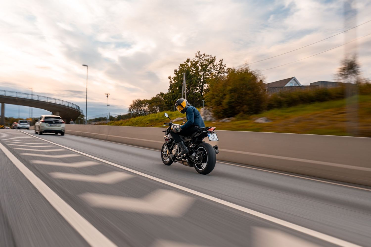 A motorcycle rider travels down an empty highway during golden hour with motion blur effects.