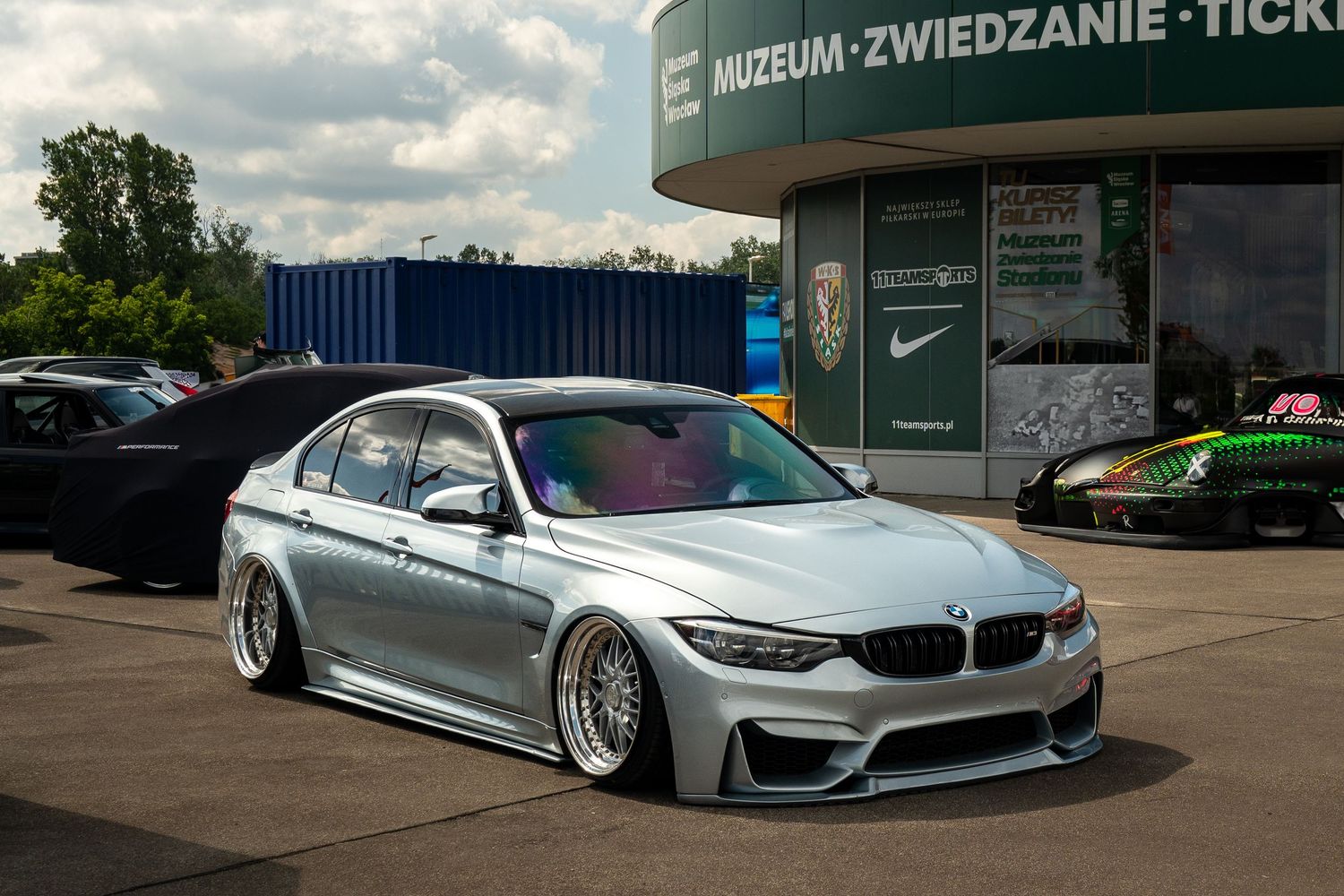 Custom modified BMW M4 with air suspension at a parking lot.