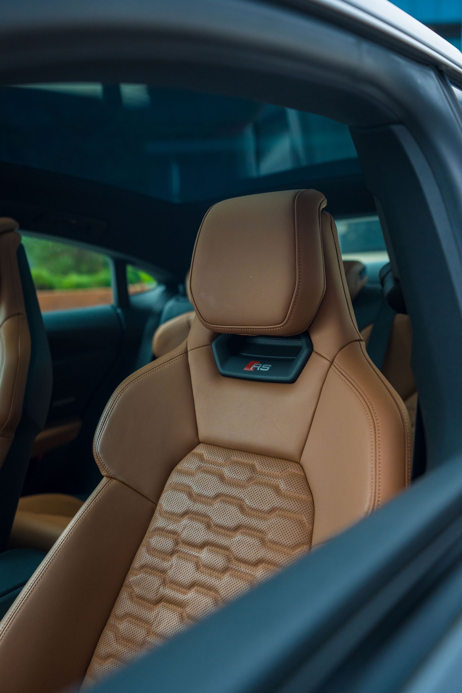 Luxurious tan leather sports seat with quilted pattern and RS badge in a modern car interior.