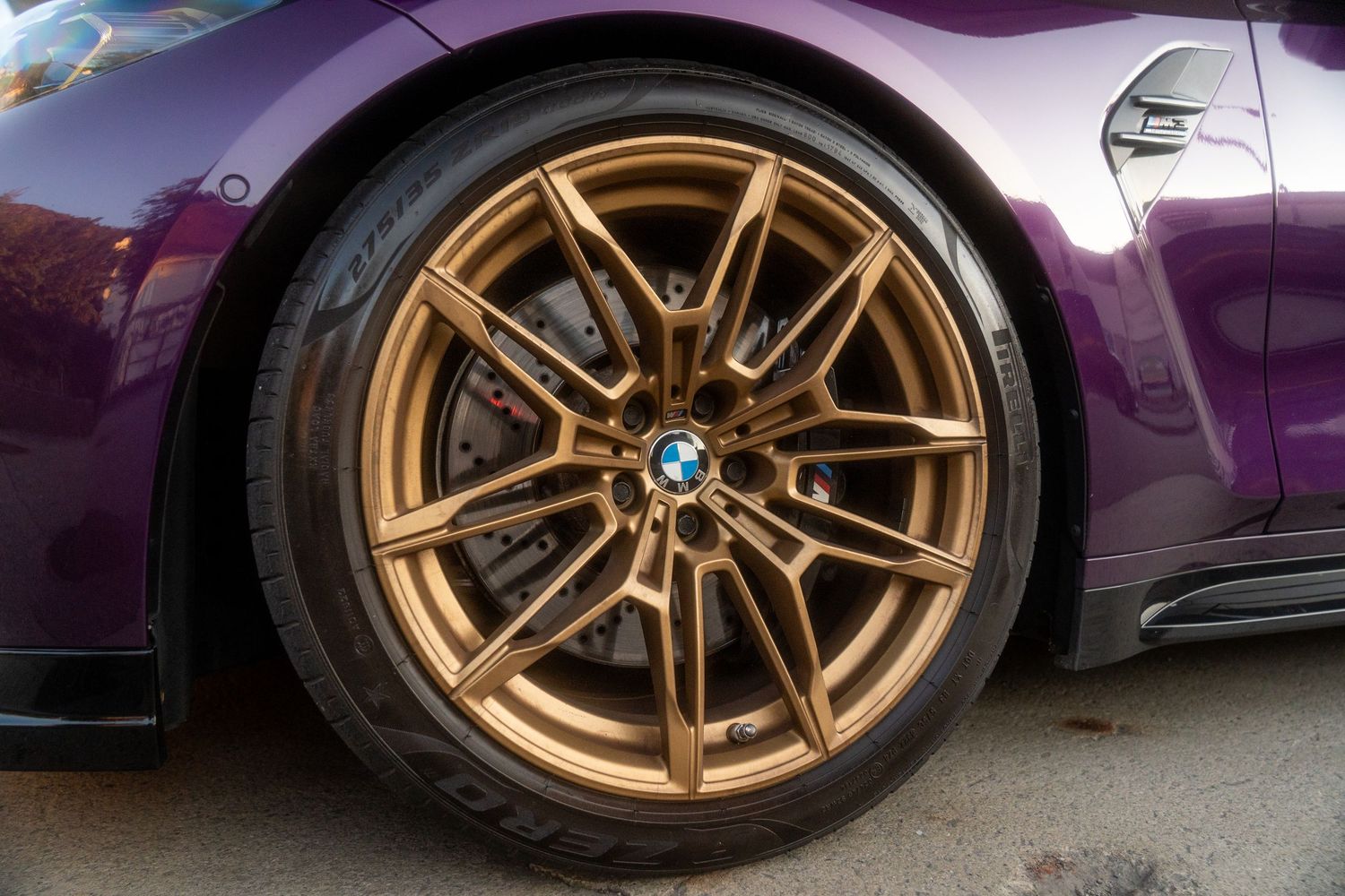 Close-up view of gold BMW M-sport wheels on a purple car showing sporty multi-spoke design and performance tires.