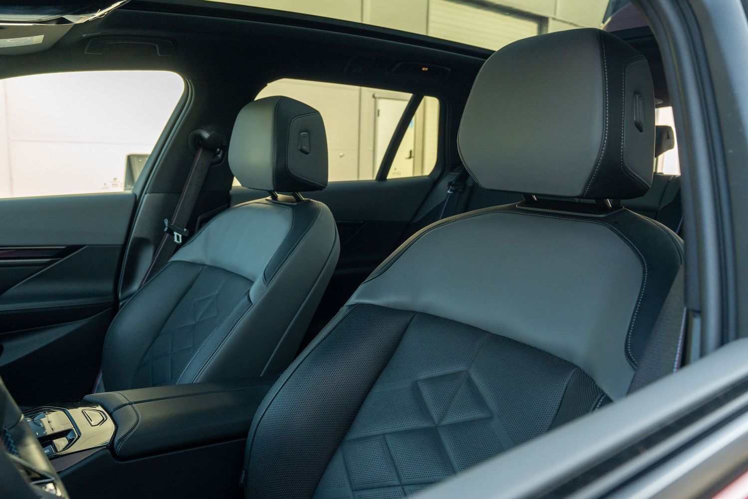 Front leather seats of BMW with diamond-pattern stitching and headrests.
