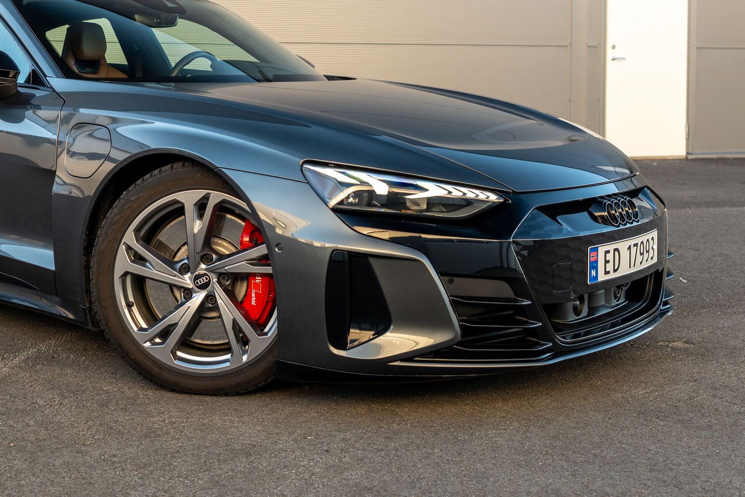Front quarter view of Audi e-tron GT showing sleek headlight and wheel design.