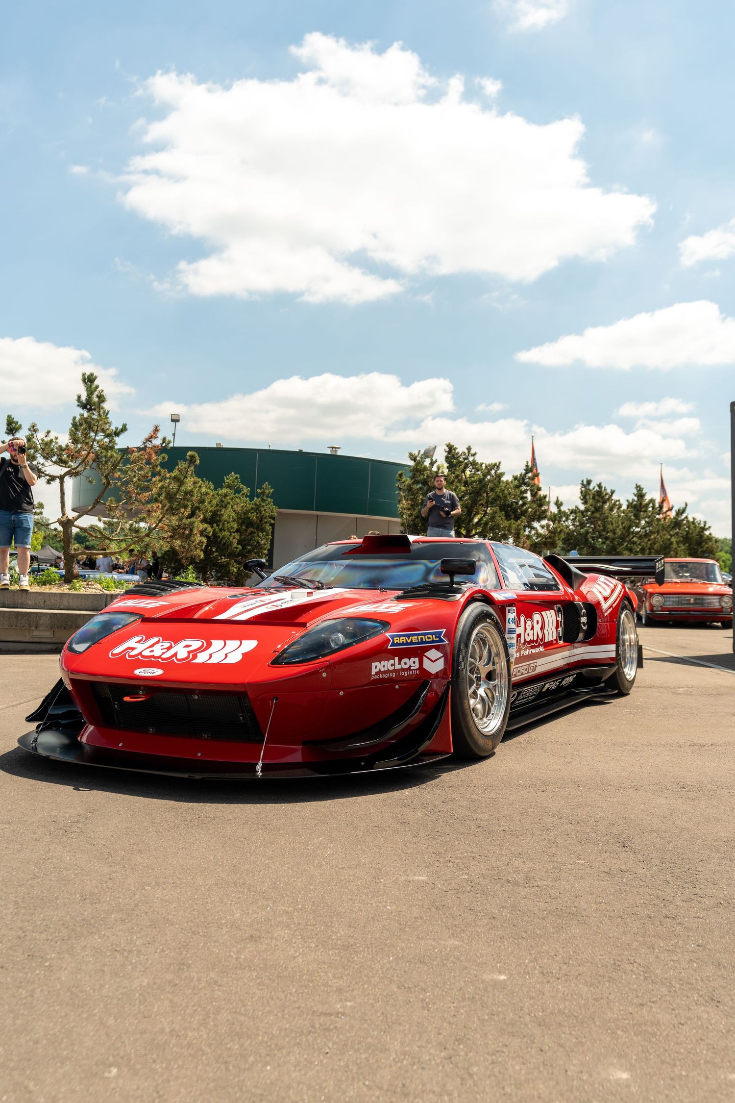 Red racing Ferrari sports cars on display at an outdoor motorsport event.