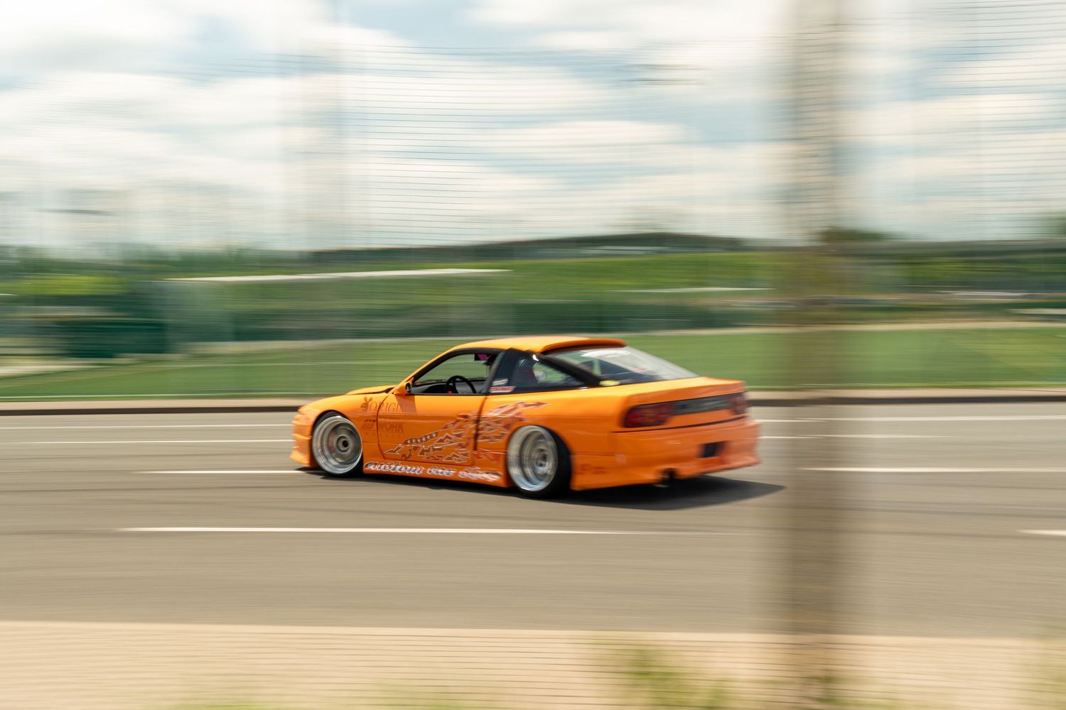 An orange Porsche 911 GT3 speeds along a racetrack with motion blur effects visible in the background.