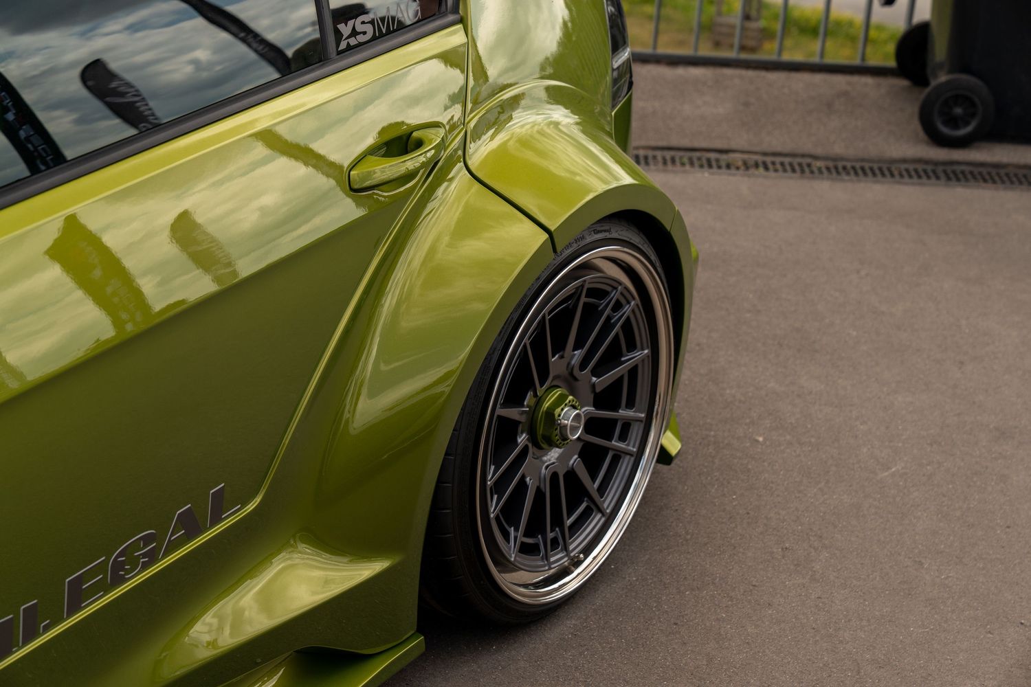 Close-up of custom black wheel fitment on lime green modified vehicle.