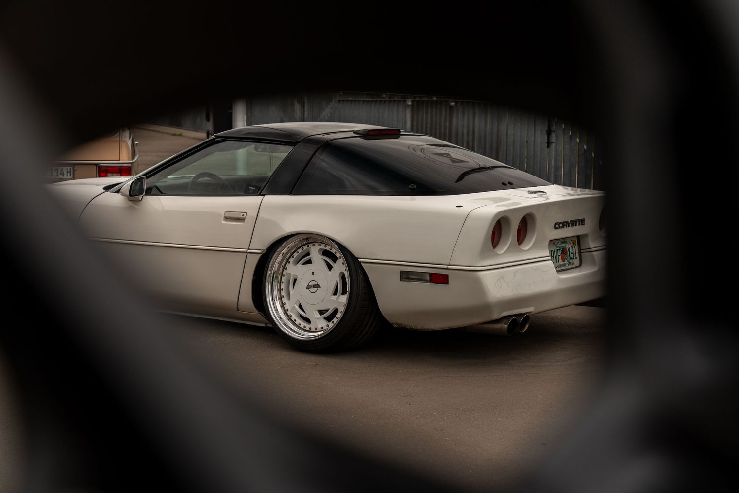 Side profile of lowered vintage Corvette seen through creative framing.
