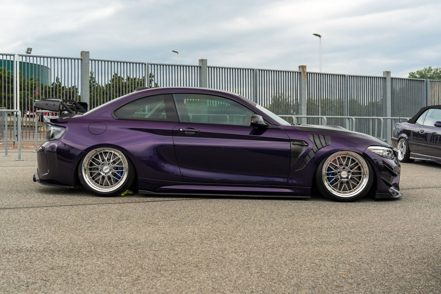 Custom purple BMW sedan with lowered suspension and polished multi-spoke wheels.