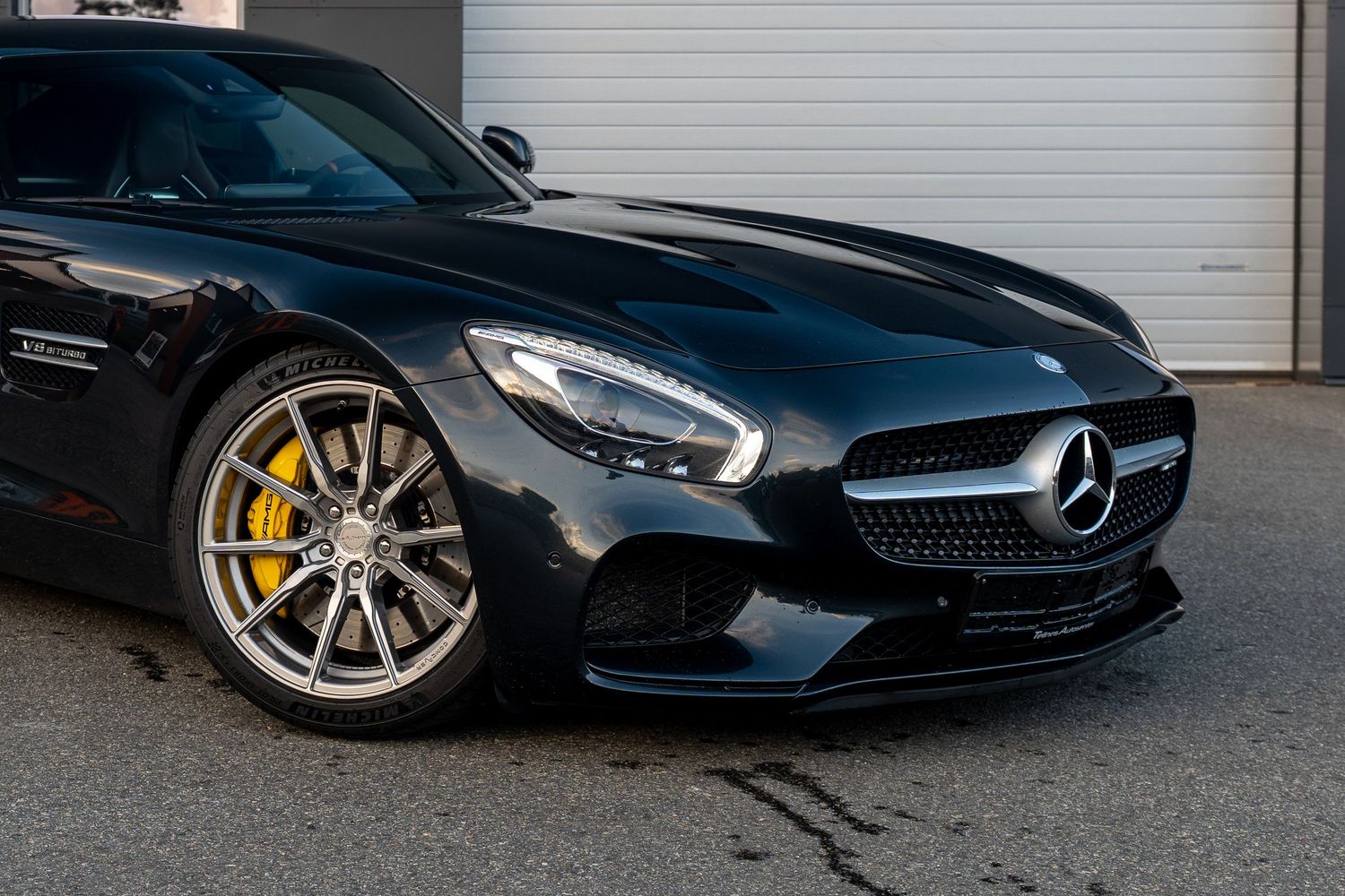 Black Mercedes-AMG GT with yellow brake calipers and silver alloy wheels viewed from front quarter.