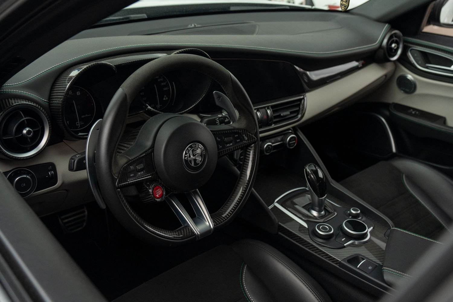 Modern black luxury car interior showing steering wheel, dashboard and center console with premium finishes.