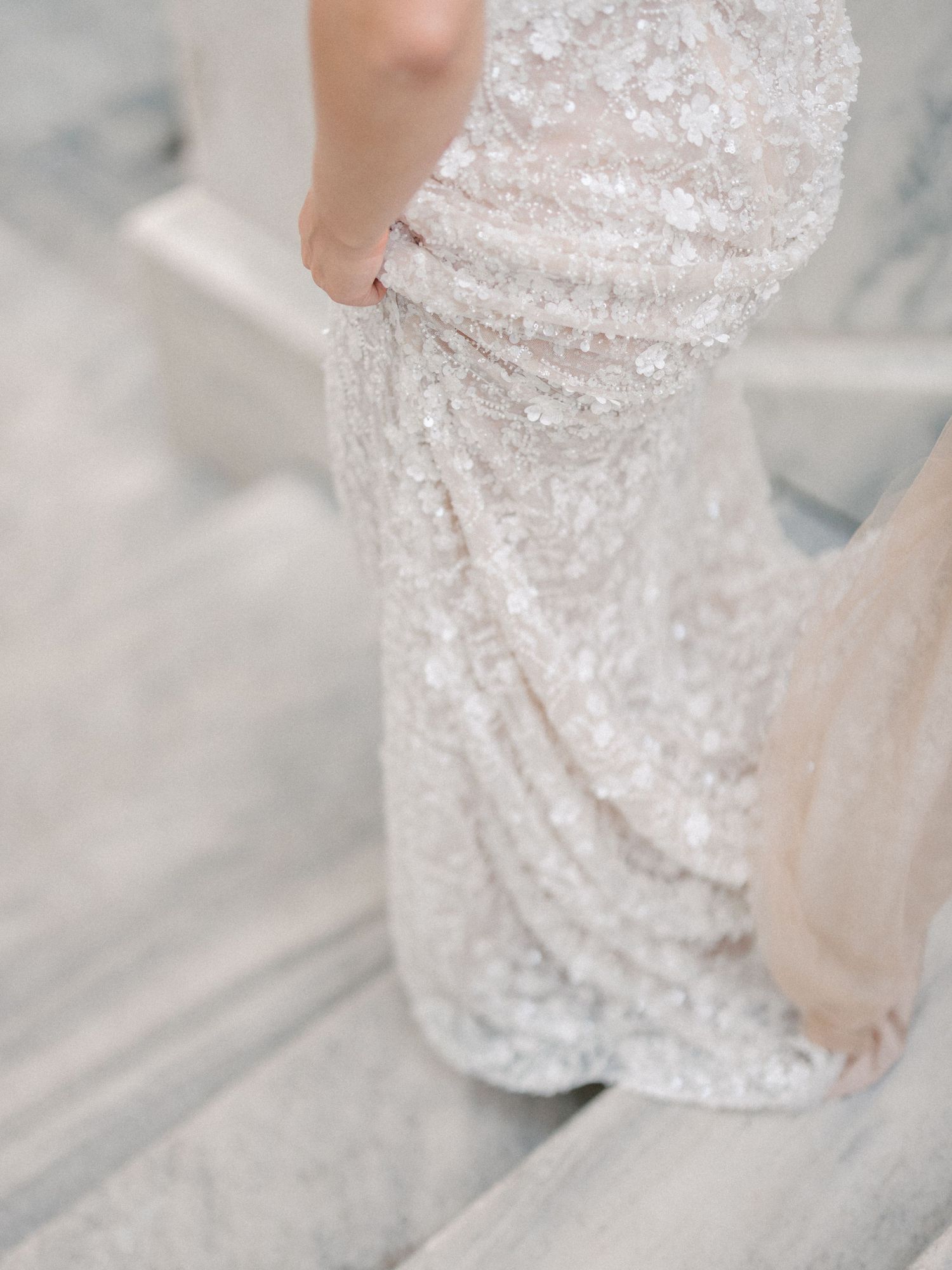 Close-up detail of sequined wedding dress fabric showing intricate beadwork.