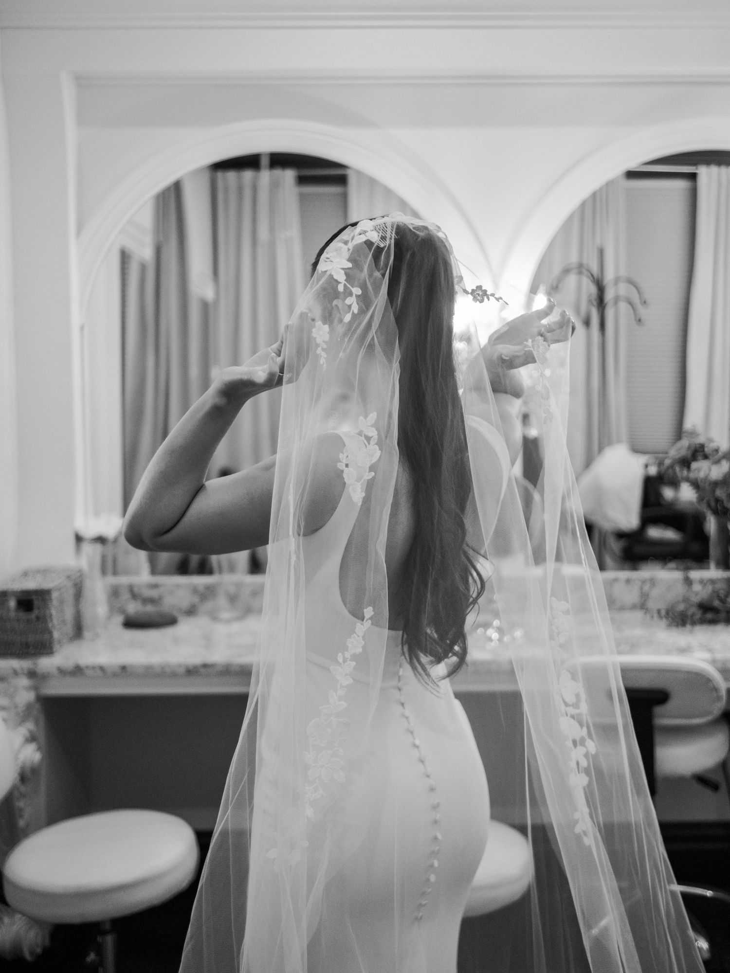 Wedding dress detail showing delicate veil and button closure in classic black and white.