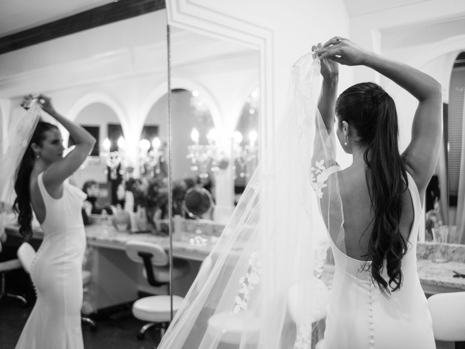 Wedding preparation scene with mirror reflection showing veil adjustment.
