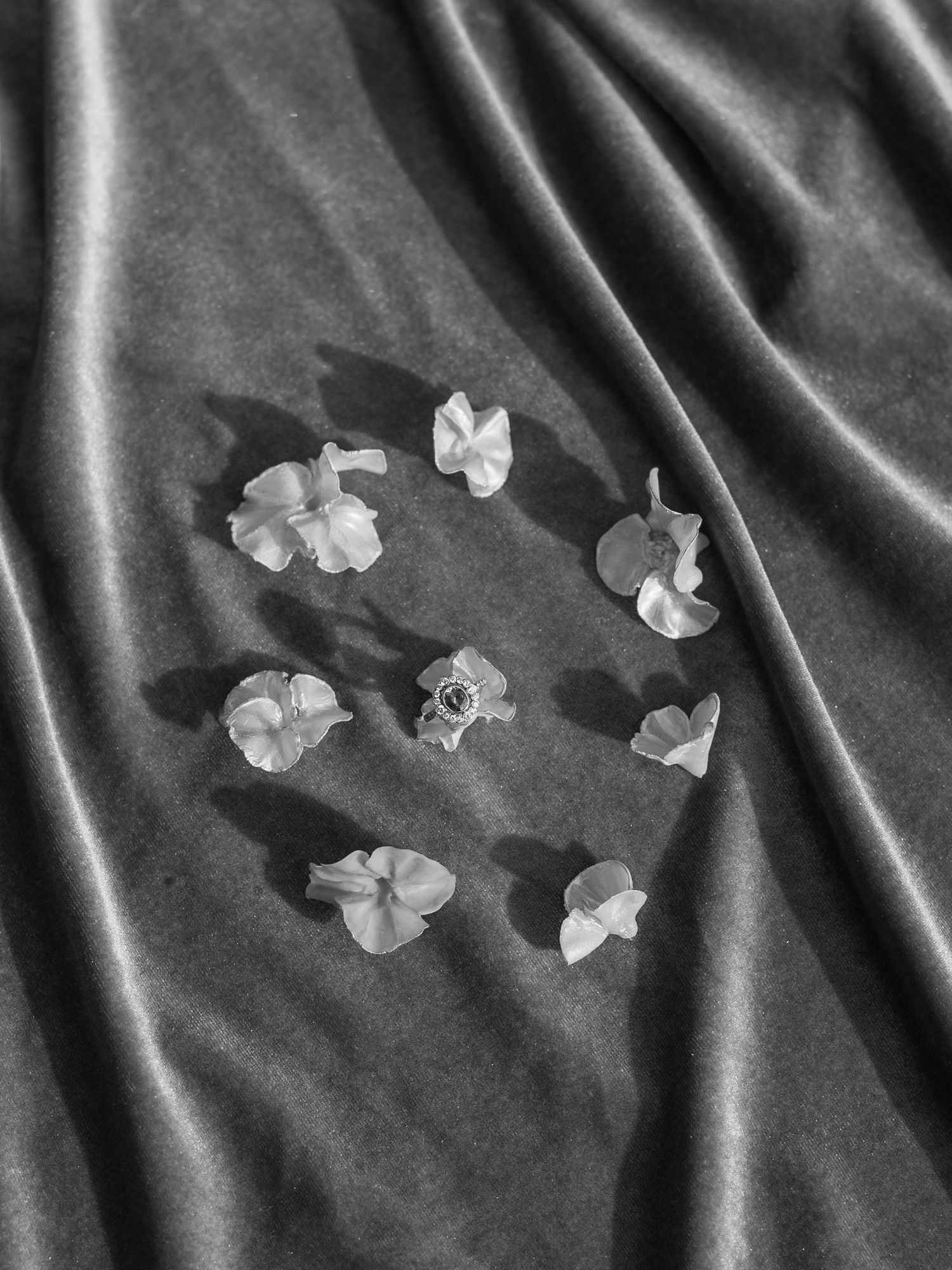 Small white flowers arranged in a circular pattern on dark gray fabric background.