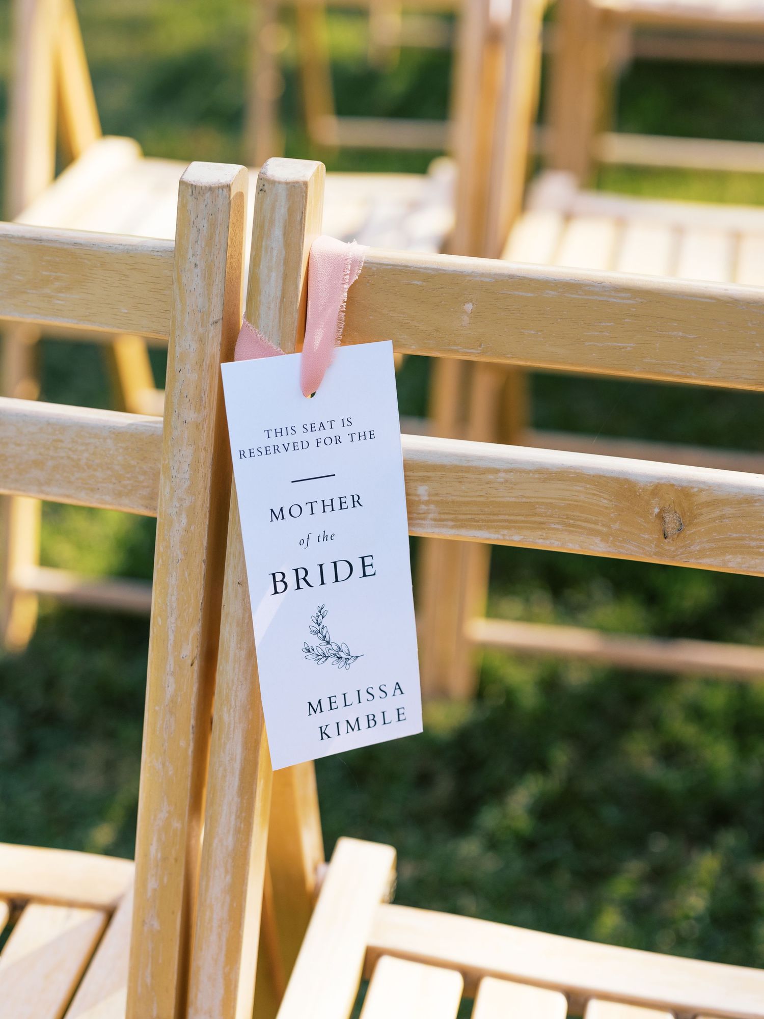 Reserved seating tag for Mother of the Bride hanging on a wooden folding chair.