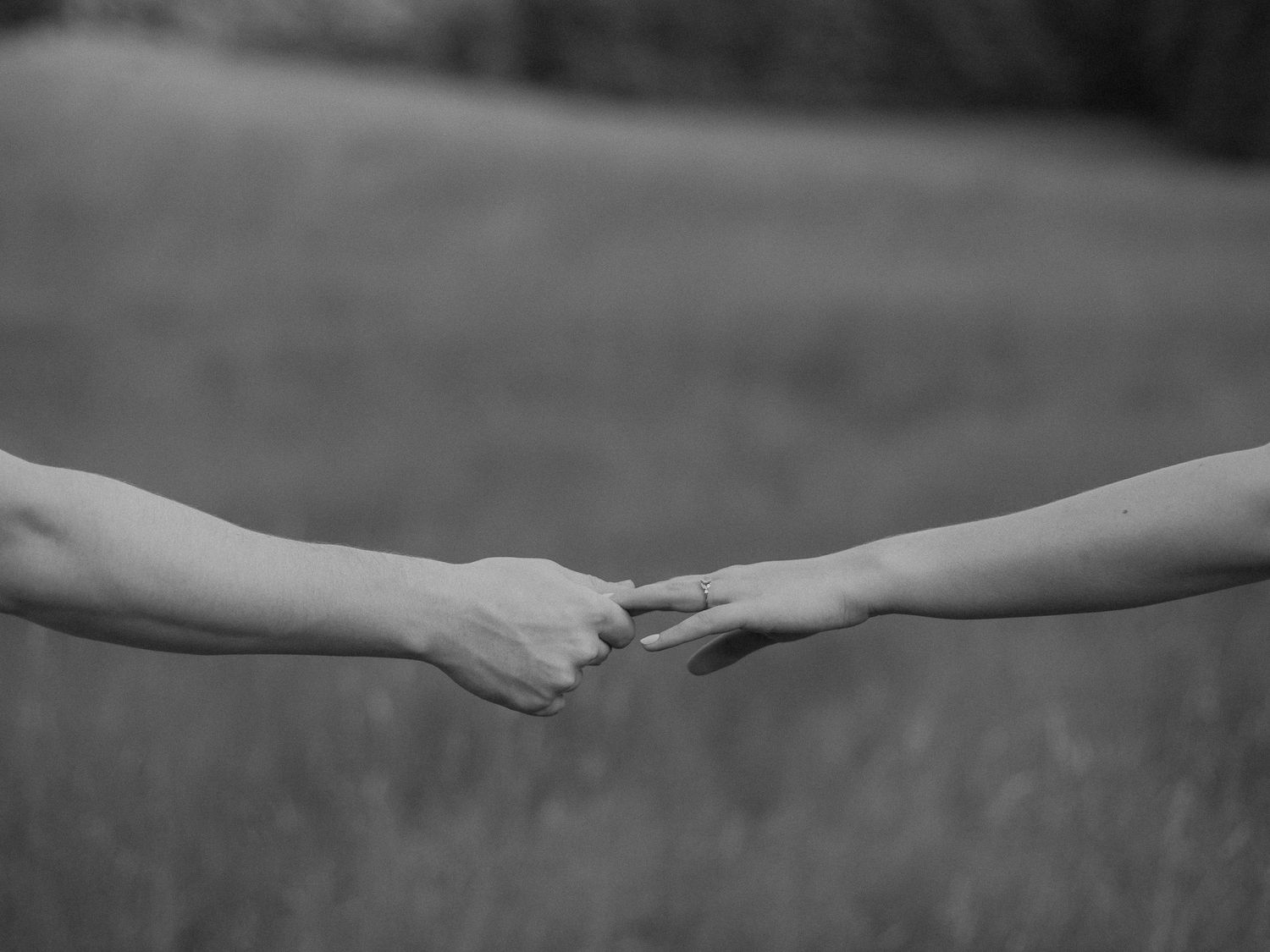 Black and white photo of hands reaching out to touch in a romantic gesture.
