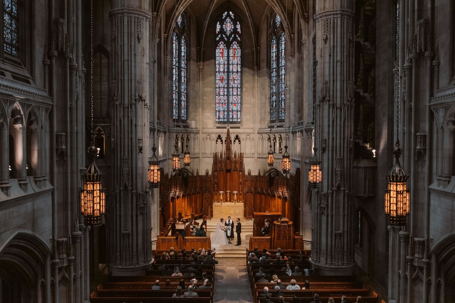 Gothic cathedral interior with dramatic lighting during wedding ceremony.