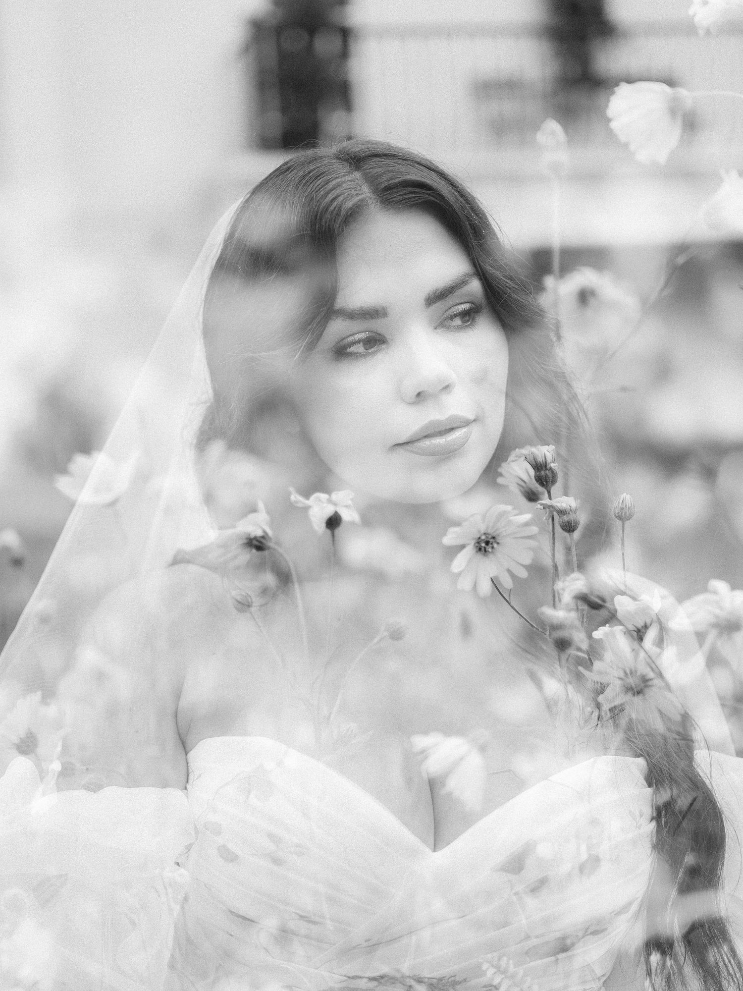 Romantic black and white bridal portrait with delicate flowers and veil creating a dreamy ethereal effect.