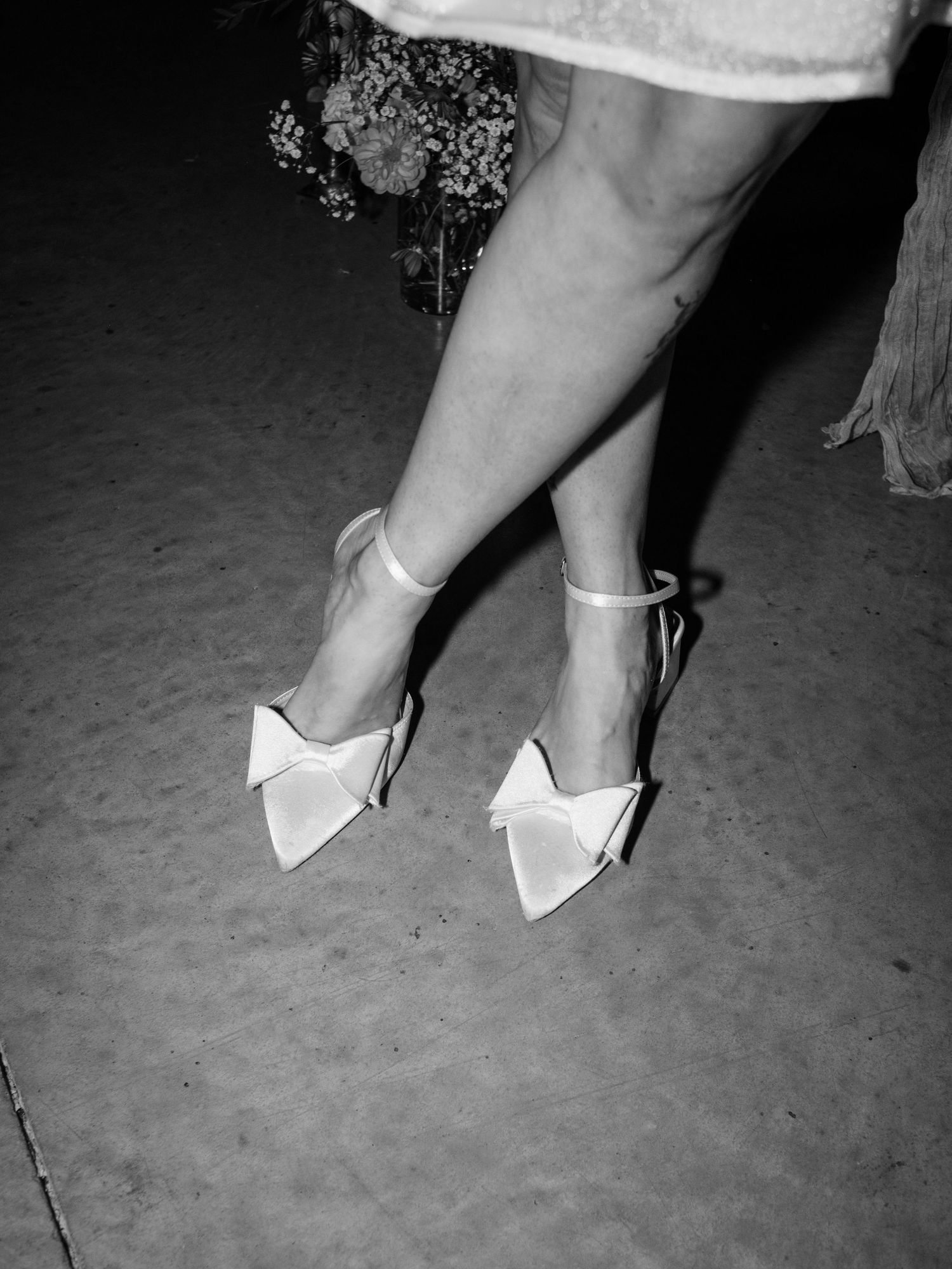 Elegant white bow flats worn with lace hem detail in black and white photography.