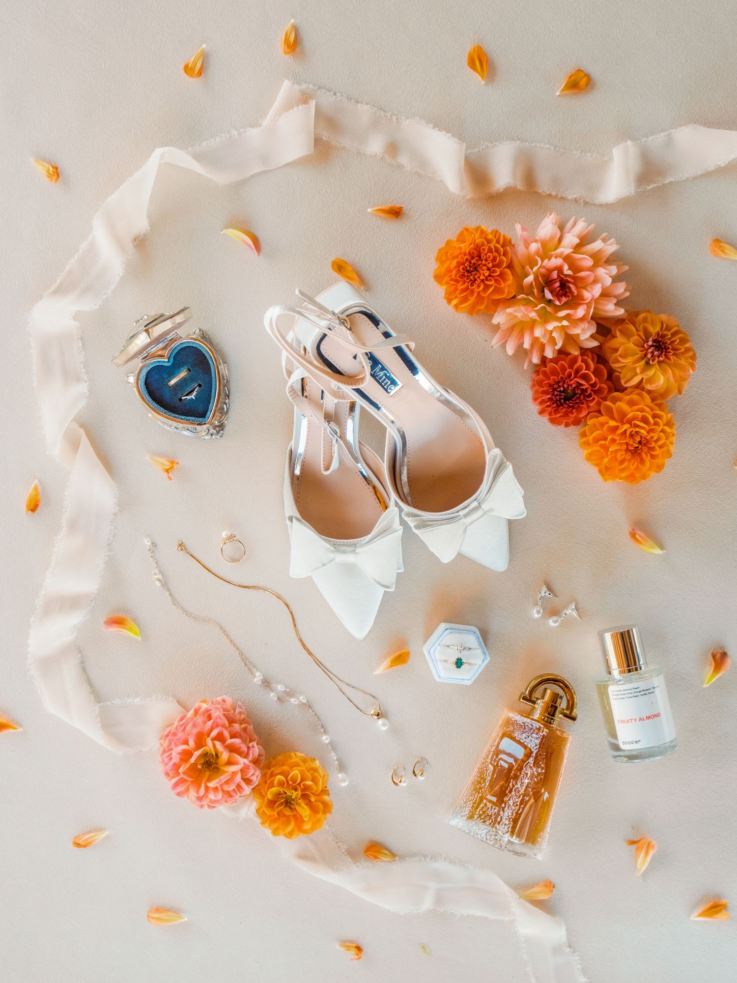 Wedding details flatlay with white shoes, perfume, flowers and accessories on beige background.