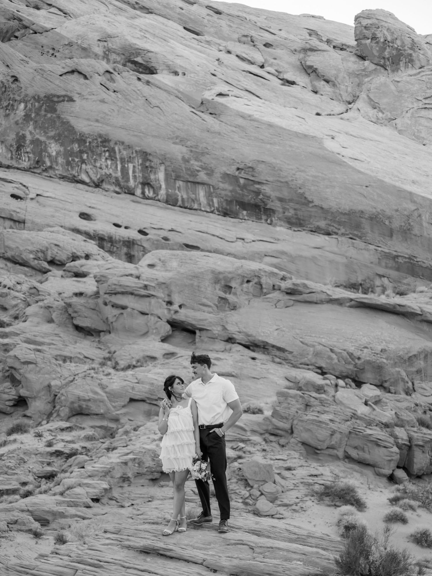 Wedding couple posing against dramatic desert rock formations in romantic sequence.