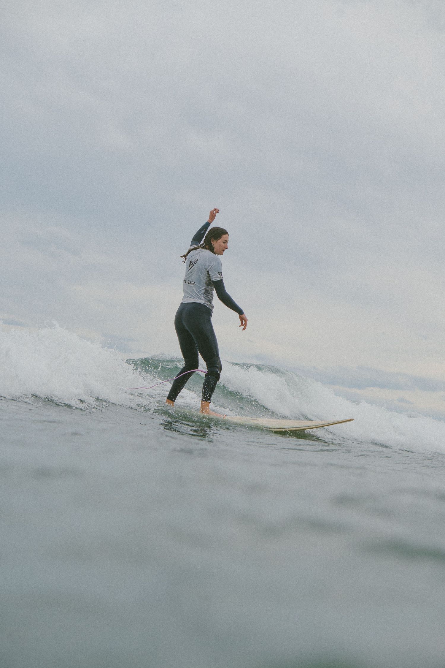 Person surfing on a longboard while riding a gentle ocean wave.