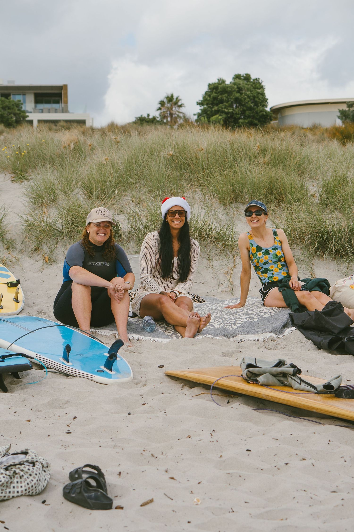 Beachgoers relaxing on the sand with surfboards and beach gear.