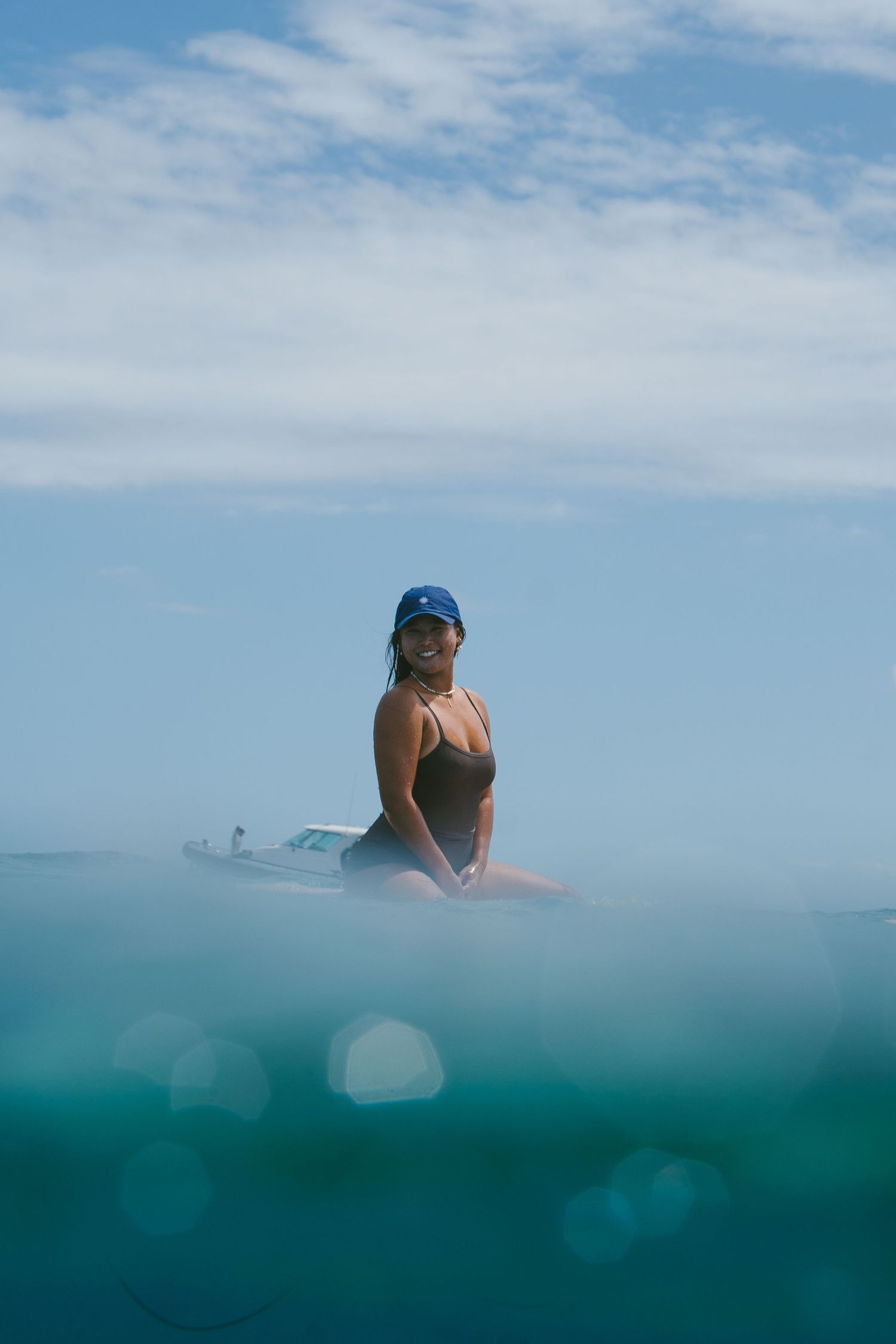Split-shot photograph showing above and below water surface with swimmer in blue ocean.