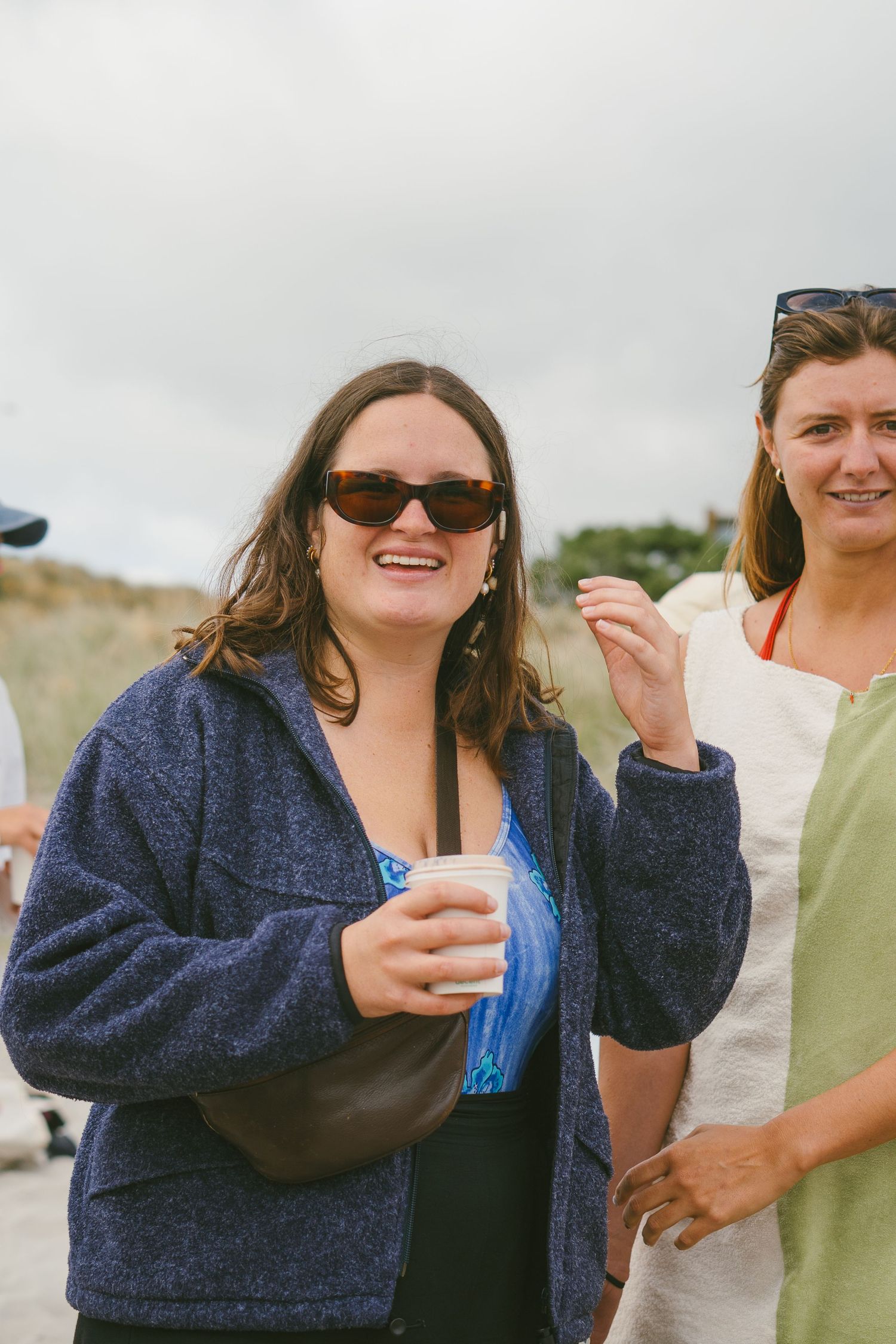 People sharing drinks and laughs on a cloudy beach day.