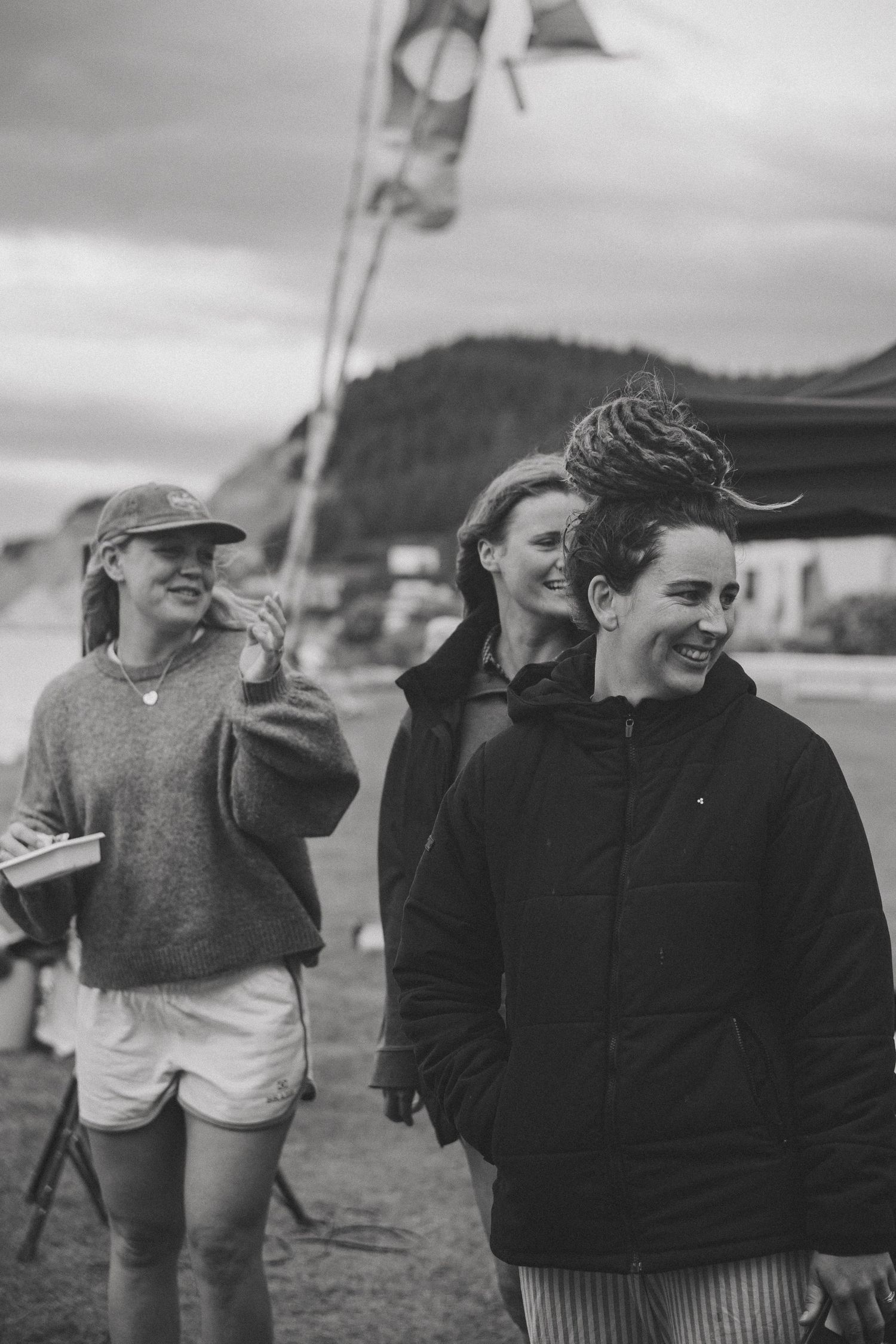Group of people gathered on beach in casual winter clothing.