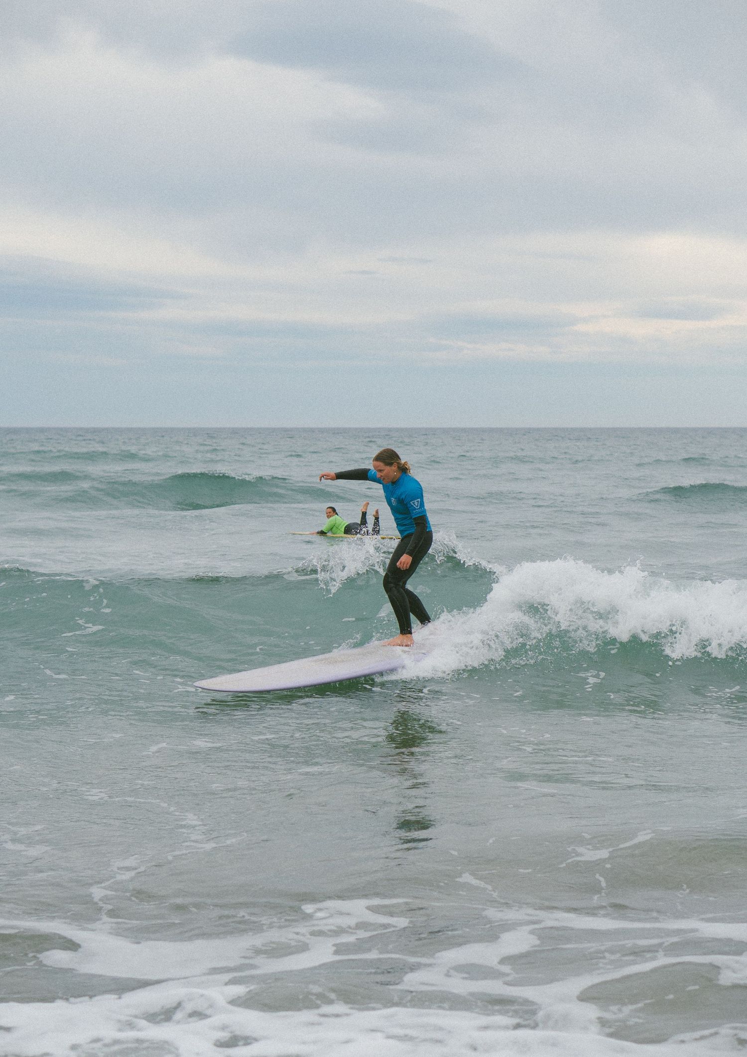 Surfer performing dynamic maneuvers on a breaking wave in choppy ocean conditions.