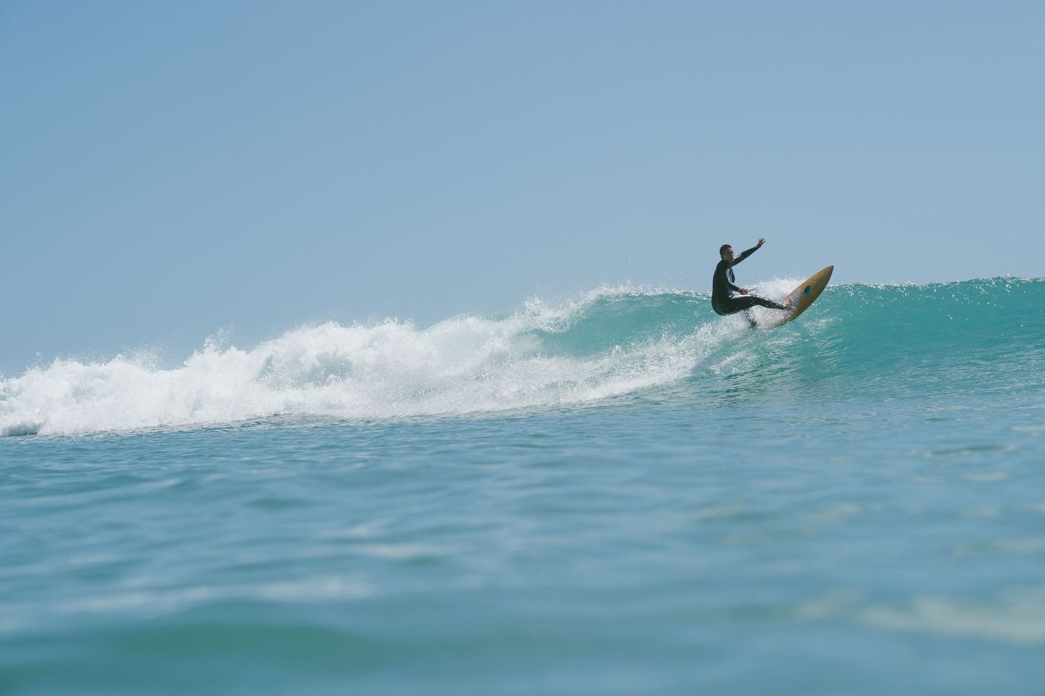 Surfer executes an impressive aerial maneuver above a breaking turquoise wave.