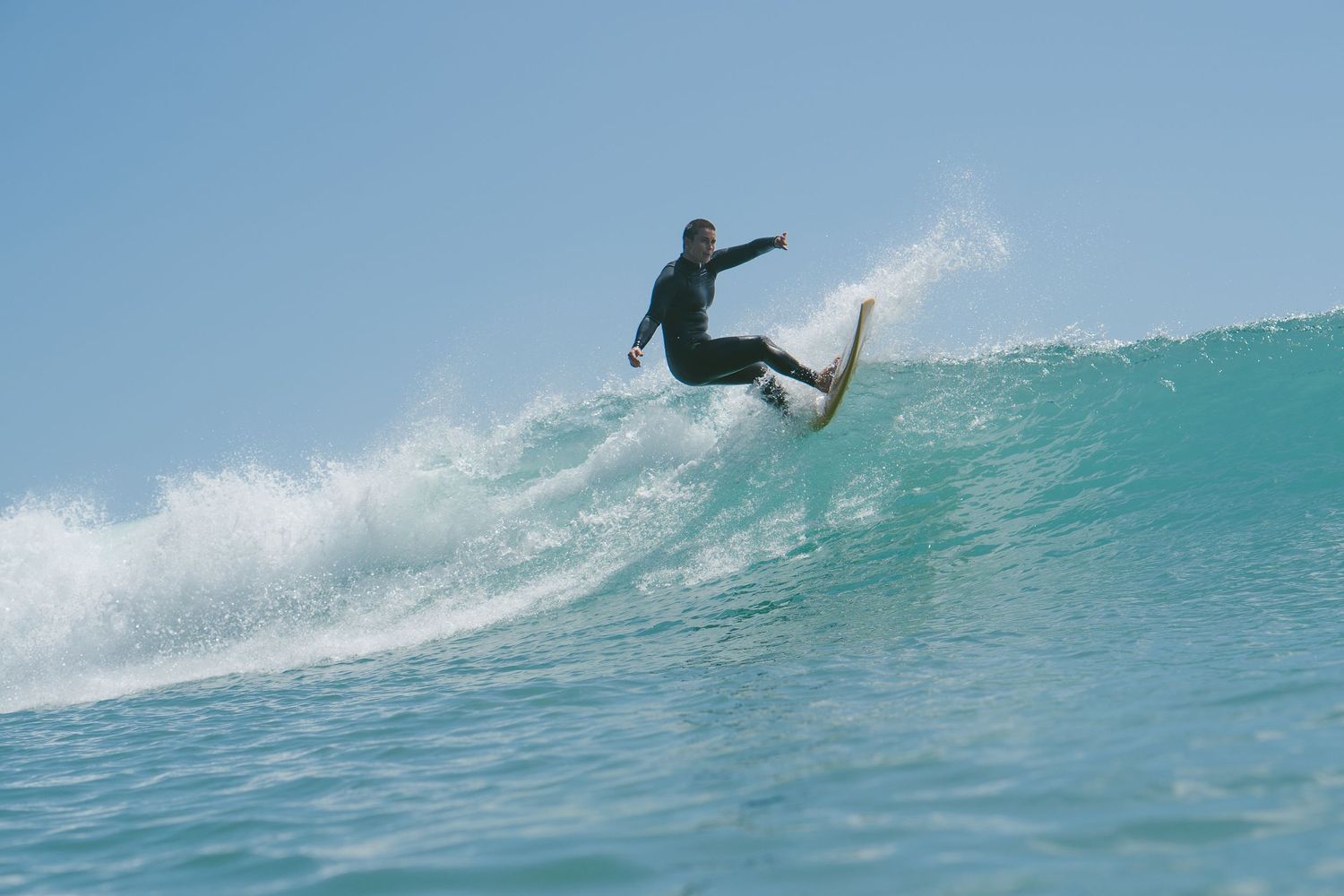 Surfer performs a stylish aerial trick above the crest of a breaking ocean wave.
