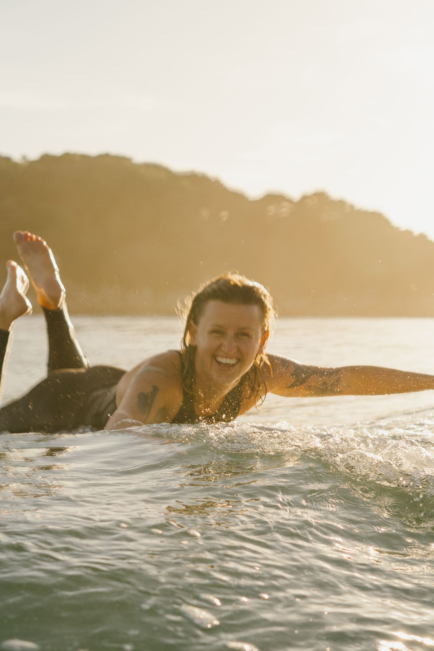 Surfer floating in calm ocean waters during golden sunset.