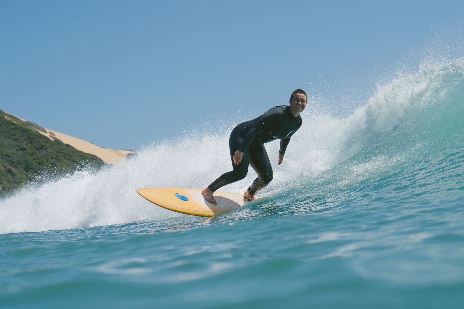 Action sequence of a surfer riding and performing tricks on a crystal clear ocean wave.