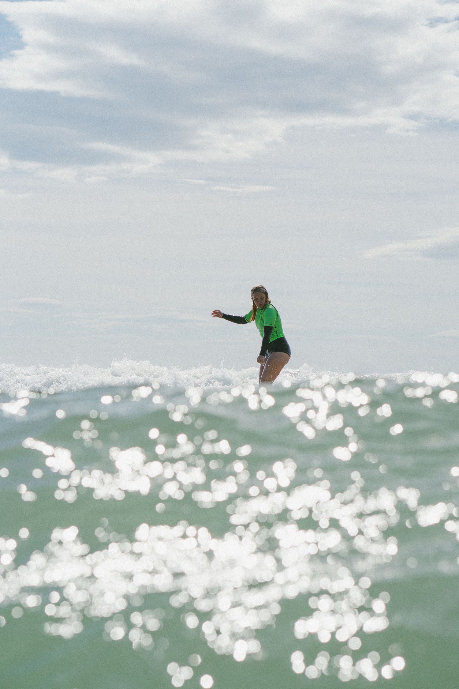 Surfer performing aerial maneuver above sparkling ocean waters.