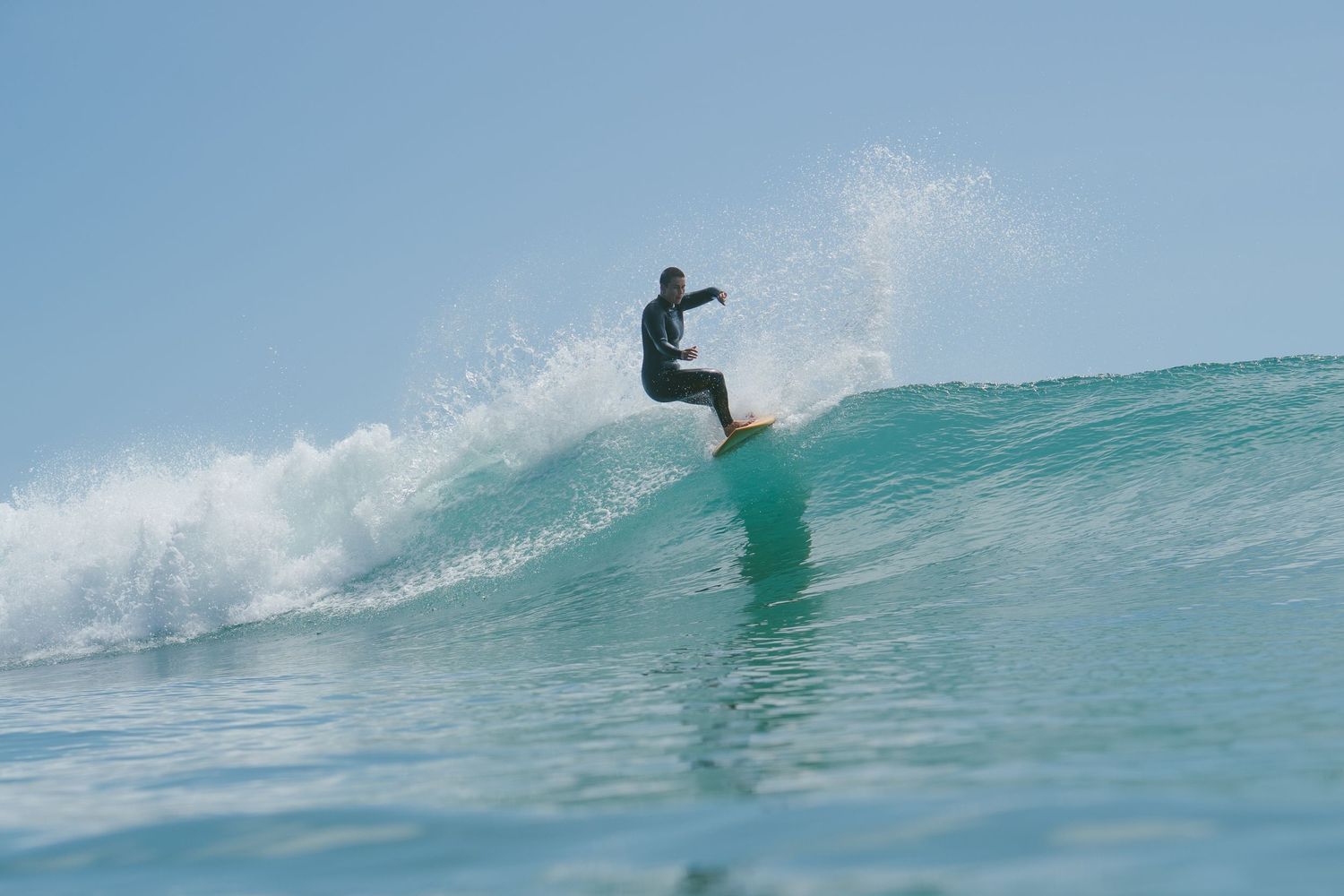 Skilled surfer performs aerial maneuvers on a clean breaking wave in tropical waters.