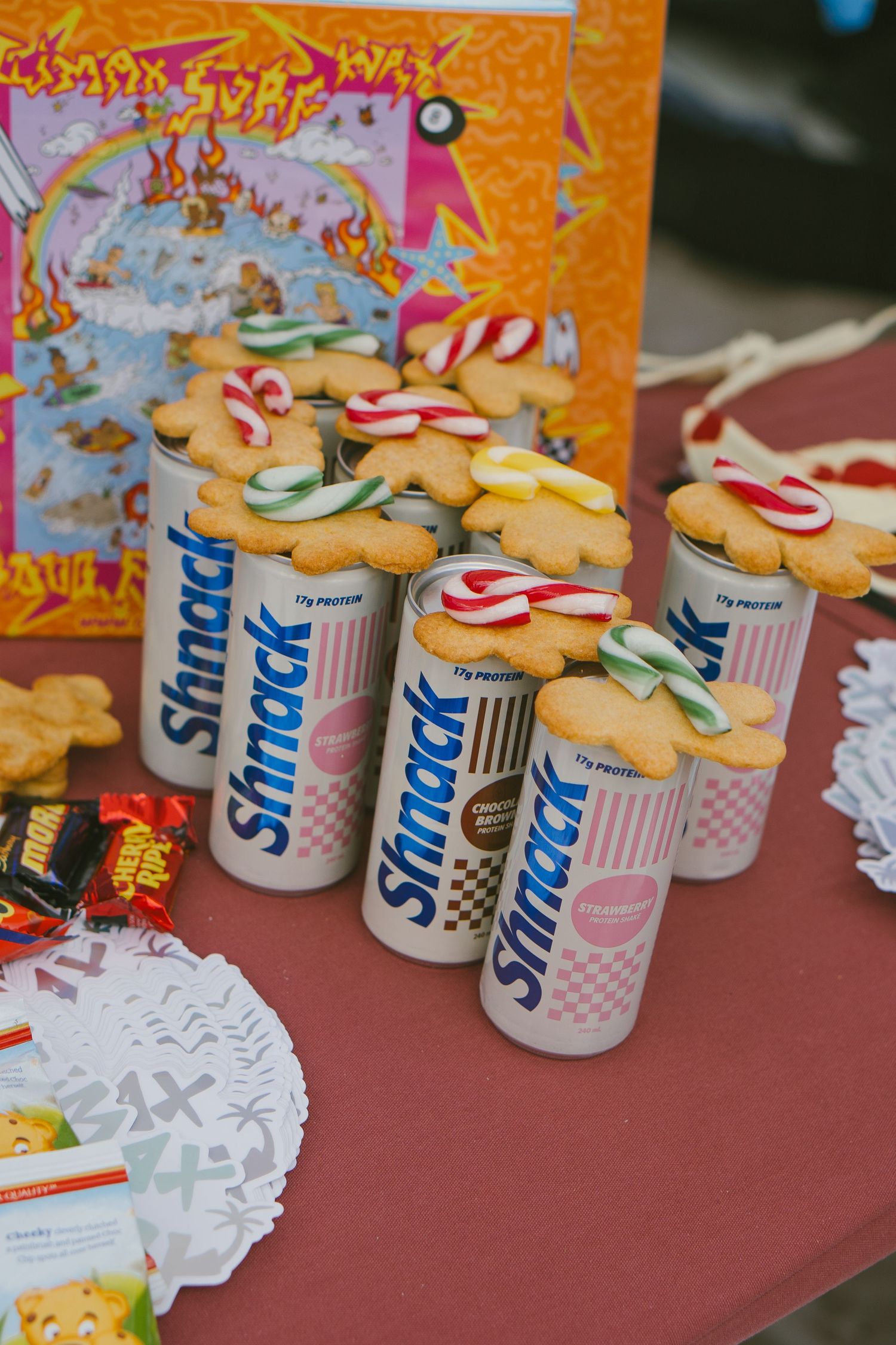 Christmas-themed display with decorated cookies and Slim Fast cans on a red tablecloth.