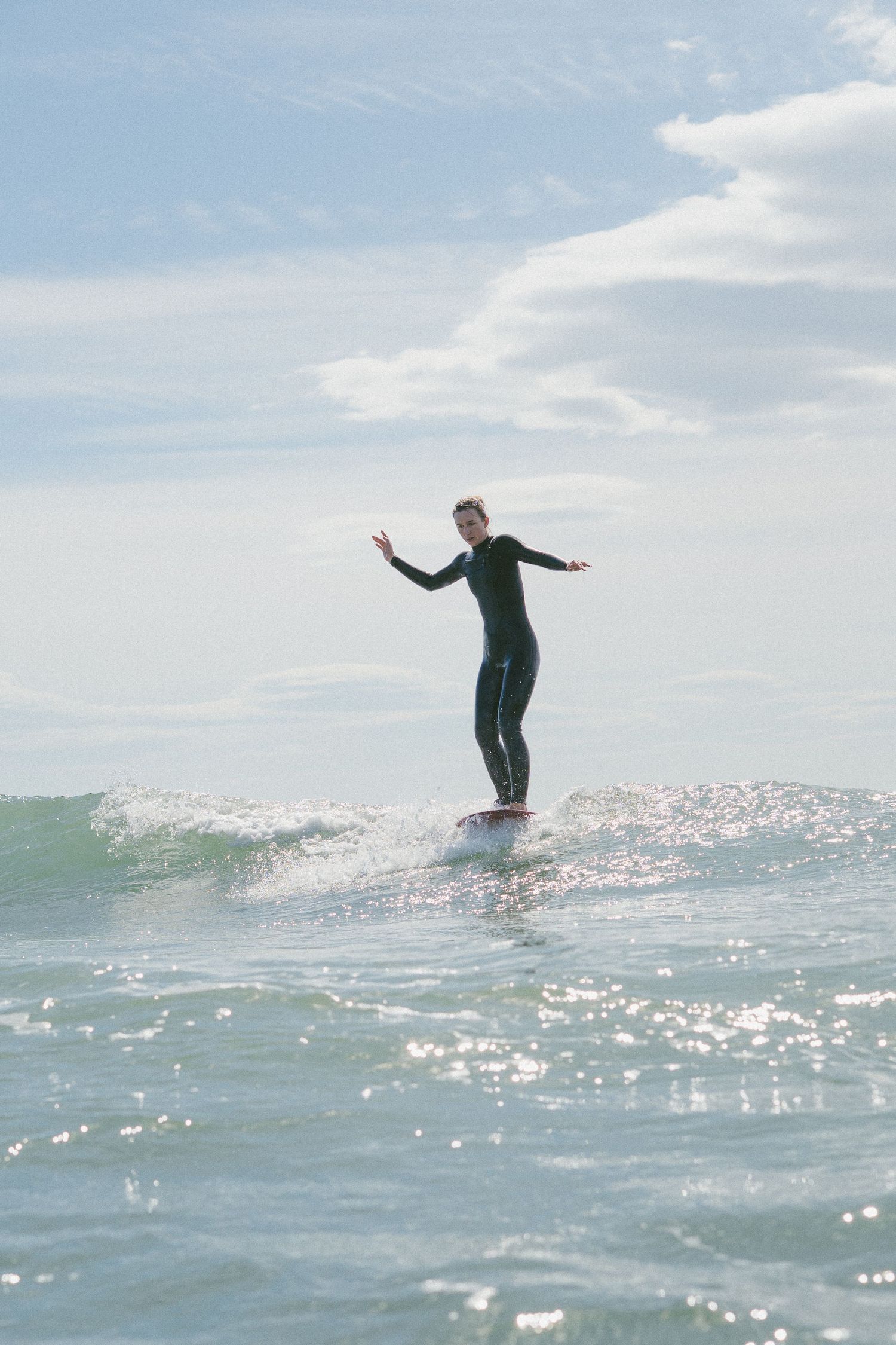 Surfer gracefully balancing on longboard in sparkling ocean waters.