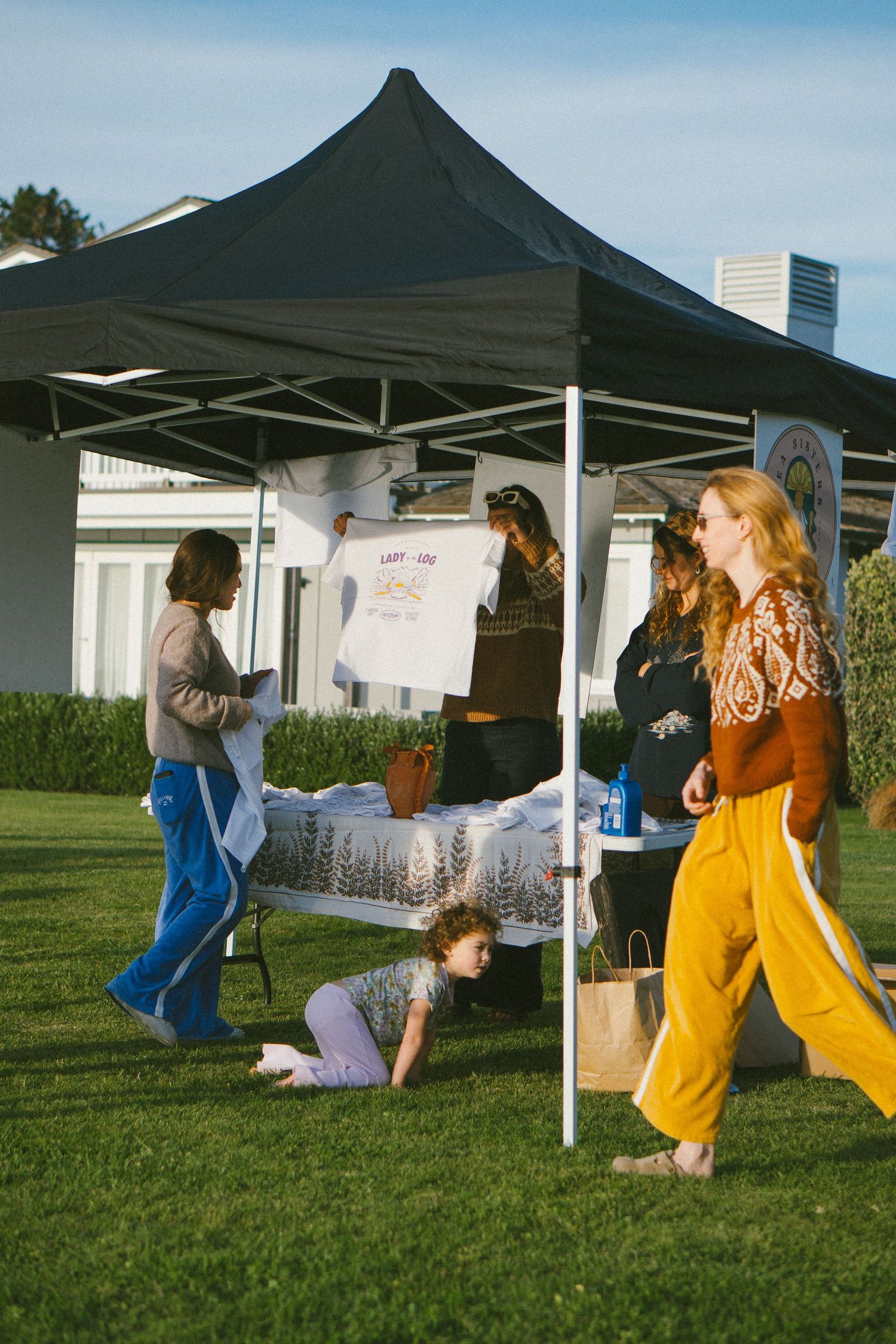 People jumping and playing under black pop-up tents on green grass field.