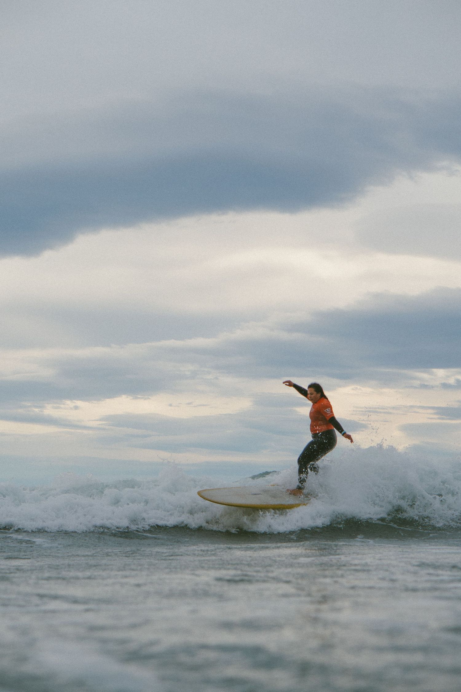 Series of action shots showing a surfer catching and riding waves under cloudy skies.