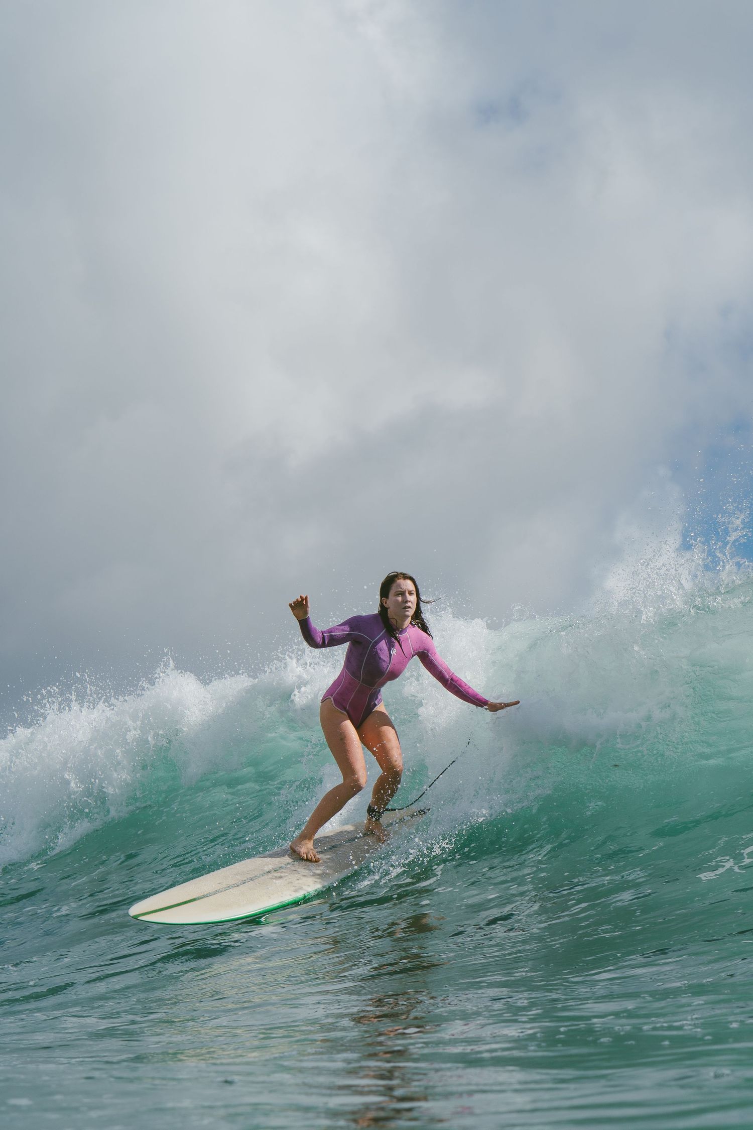 Surfer maintaining balance while riding through a breaking ocean wave.