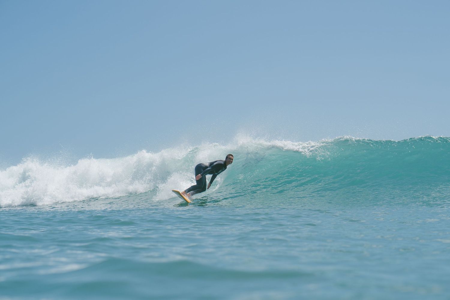 Dynamic surfing sequence shows a rider catching air off a pristine turquoise wave.